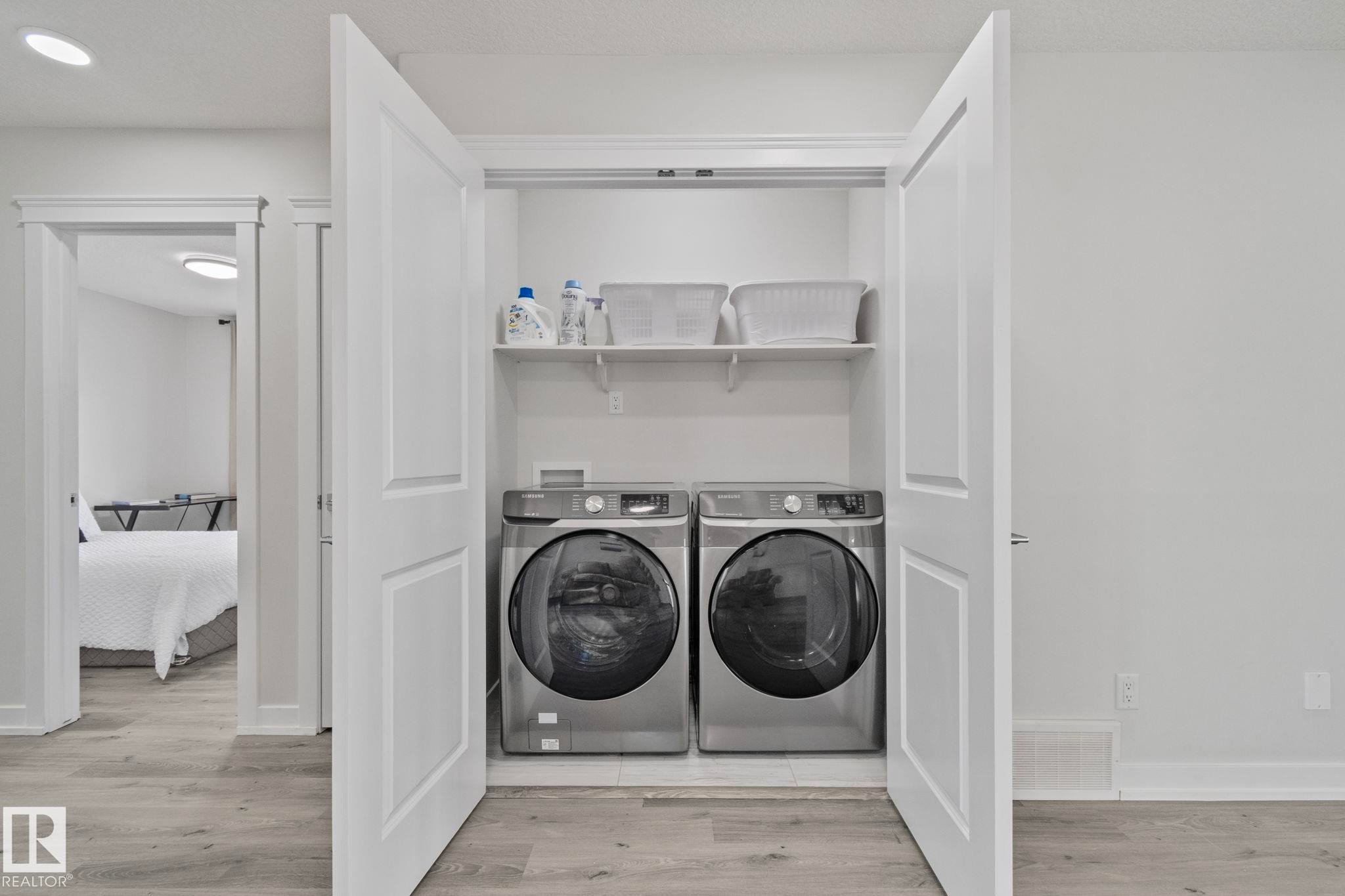 Dedicated laundry closet featuring a stainless steel washer and dryer, upper shelving, and white bi-fold doors - 334 Aston Close, Leduc, AB - Indoor Photo Showing Laundry Room