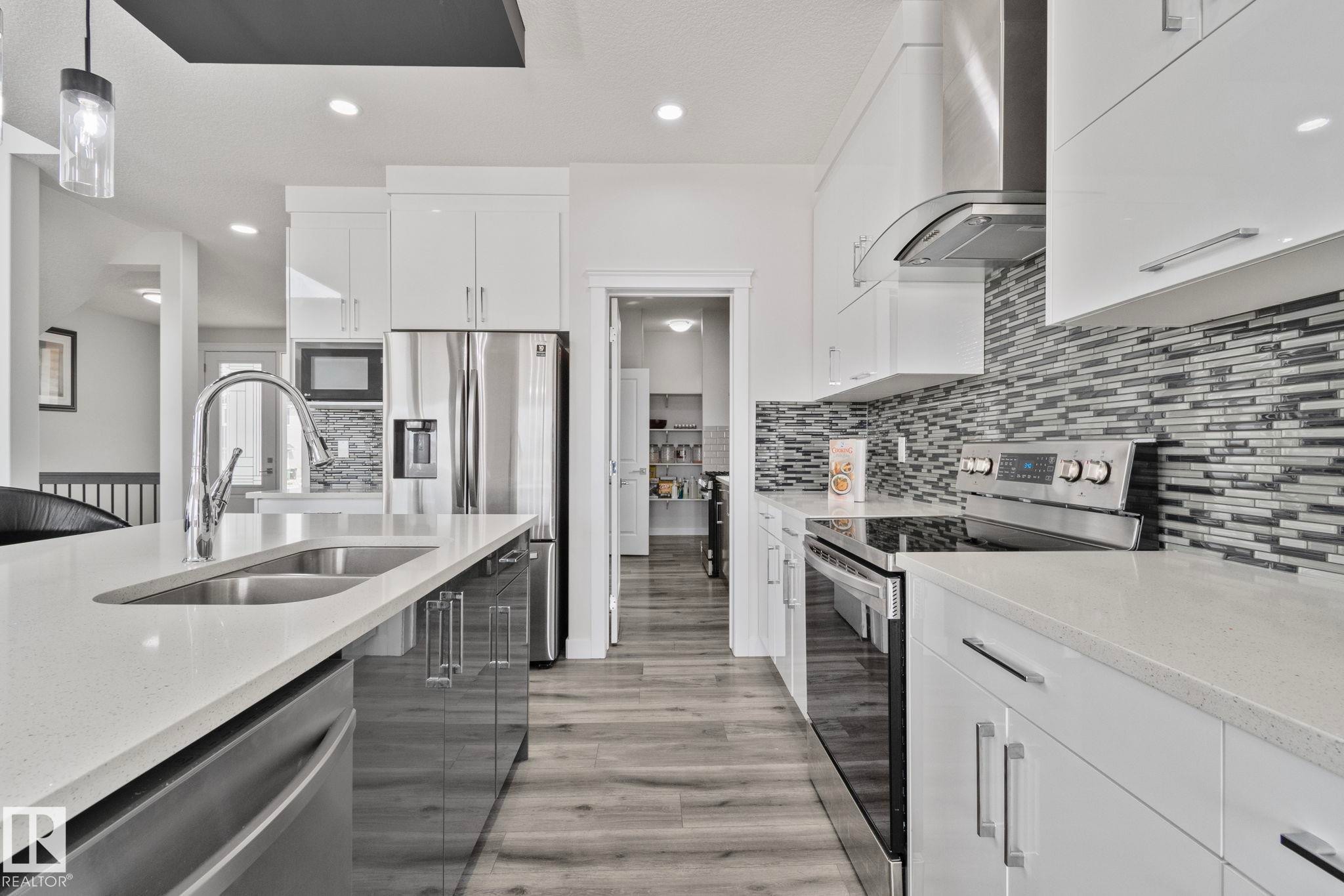 Contemporary kitchen featuring light quartz countertops and wood-finish flooring - 334 Aston Close, Leduc, AB - Indoor Photo Showing Kitchen With Double Sink With Upgraded Kitchen