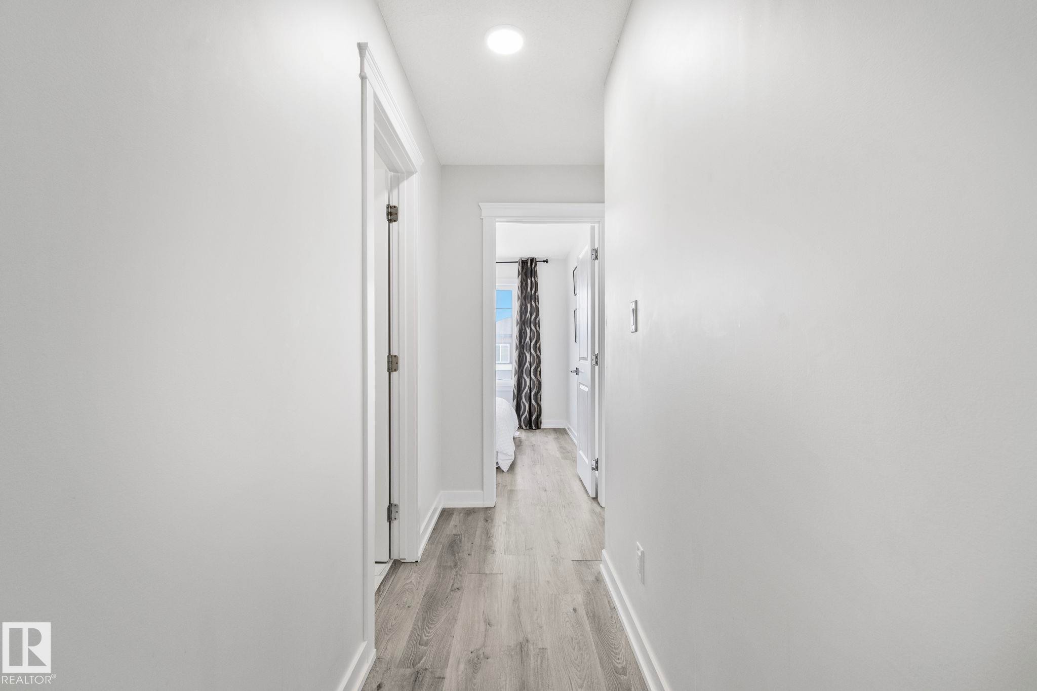 Hallway featuring wood-finish flooring, white painted walls, recessed lighting, and white baseboards - 334 Aston Close, Leduc, AB - Indoor Photo Showing Other Room
