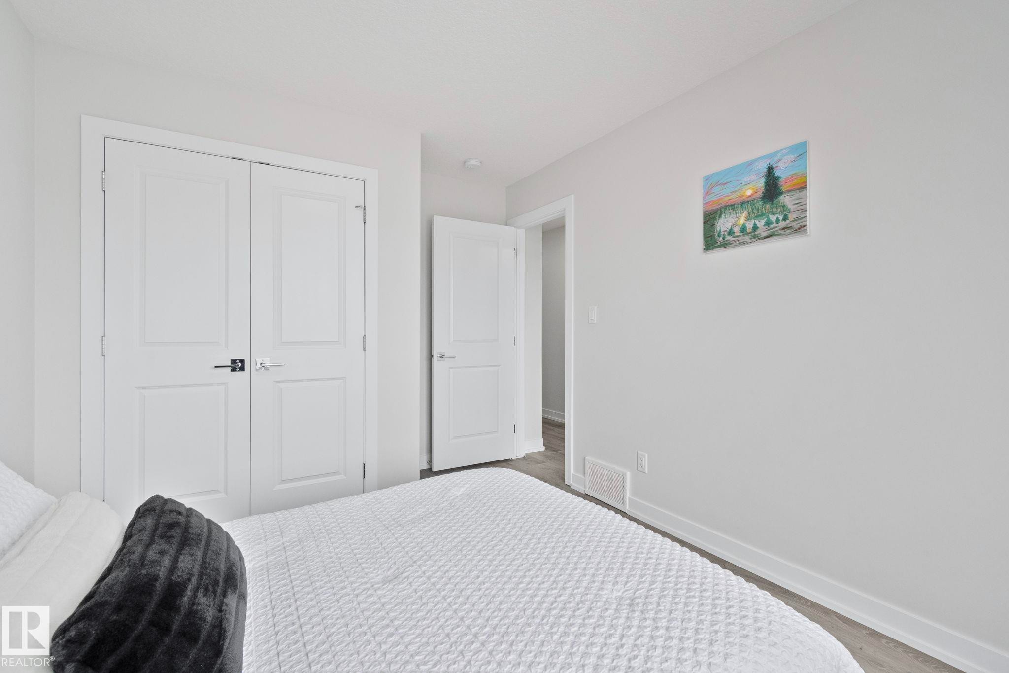 Bedroom featuring light gray walls, white trim, and wood-finish flooring - 334 Aston Close, Leduc, AB - Indoor Photo Showing Bedroom