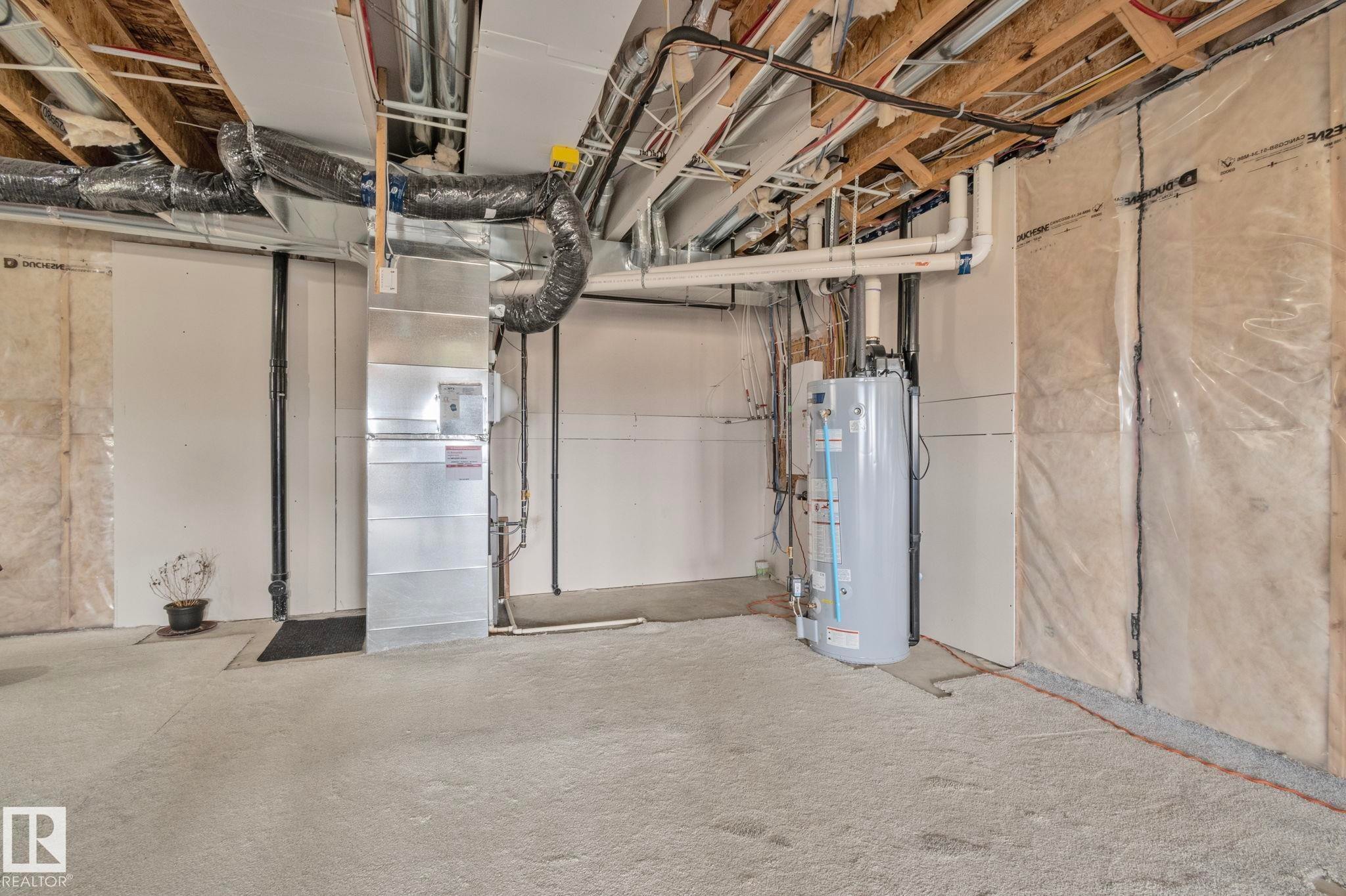 Unfinished basement featuring exposed ceiling joists, white insulated walls, visible ductwork, and a water heater - 334 Aston Close, Leduc, AB - Indoor Photo Showing Basement