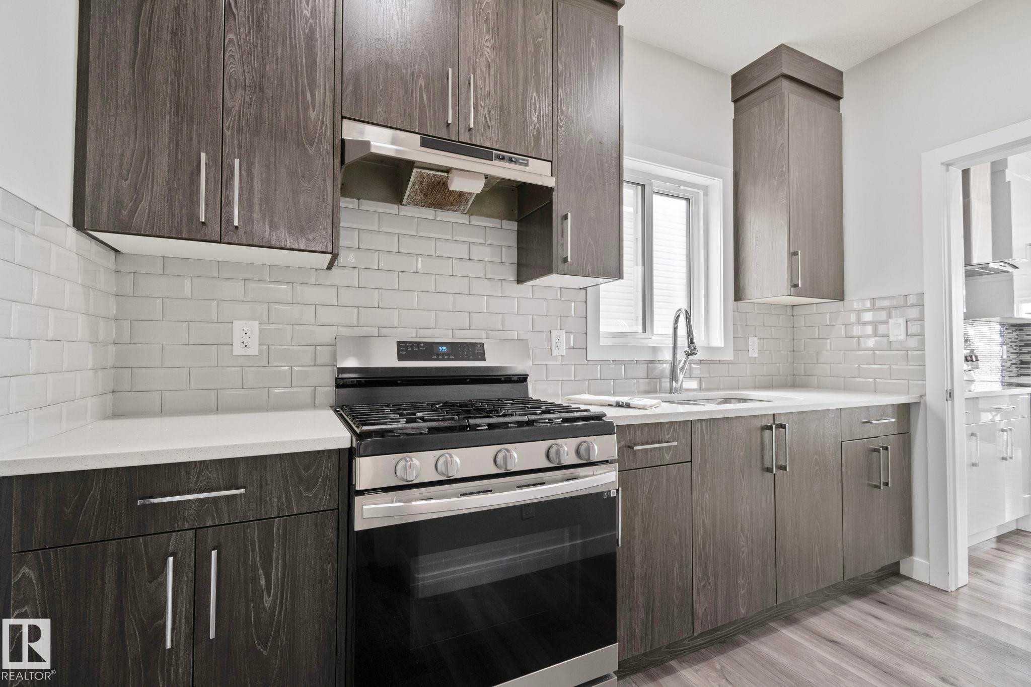 Modern kitchen featuring wood-finish cabinetry, white subway tile backsplash, and light countertops - 334 Aston Close, Leduc, AB - Indoor Photo Showing Kitchen With Upgraded Kitchen