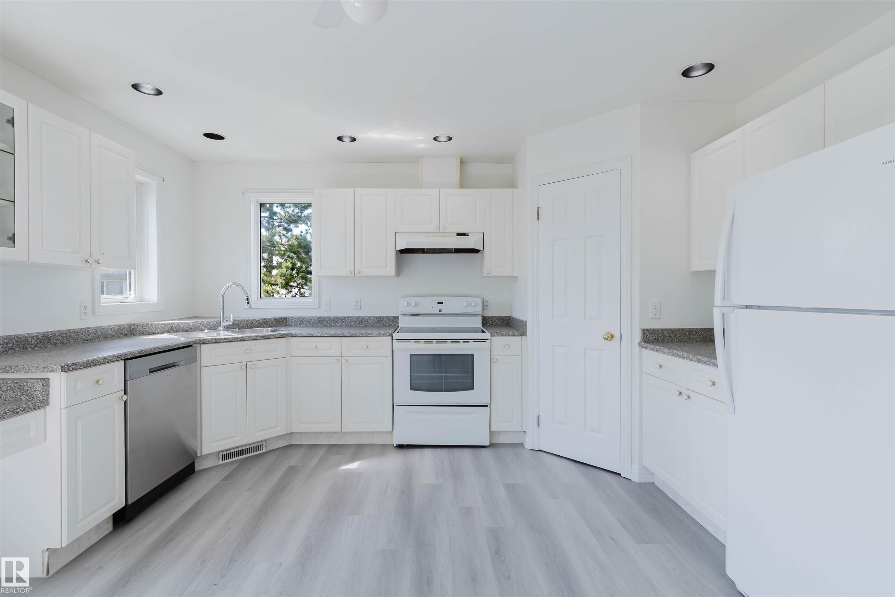 Kitchen featuring abundant white cabinetry, light-toned countertops, wood-finish flooring, a stainless steel dishwasher, and recessed ceiling lights - 13755 131B Avenue, Edmonton, AB - Indoor Photo Showing Kitchen