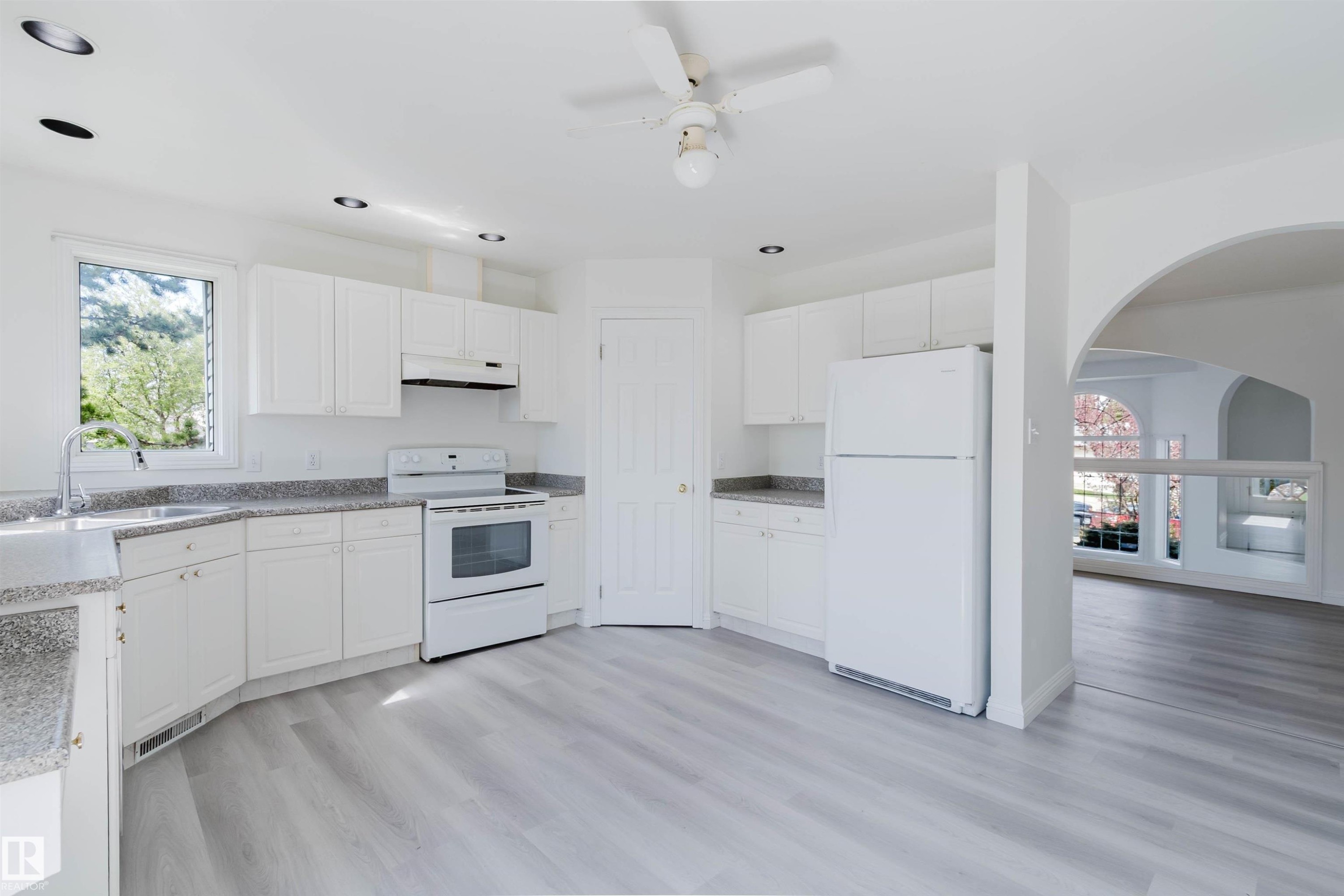 Bright kitchen featuring light wood-finish flooring, white cabinetry, a white refrigerator, a white range, and a ceiling fan - 13755 131B Avenue, Edmonton, AB - Indoor Photo Showing Kitchen