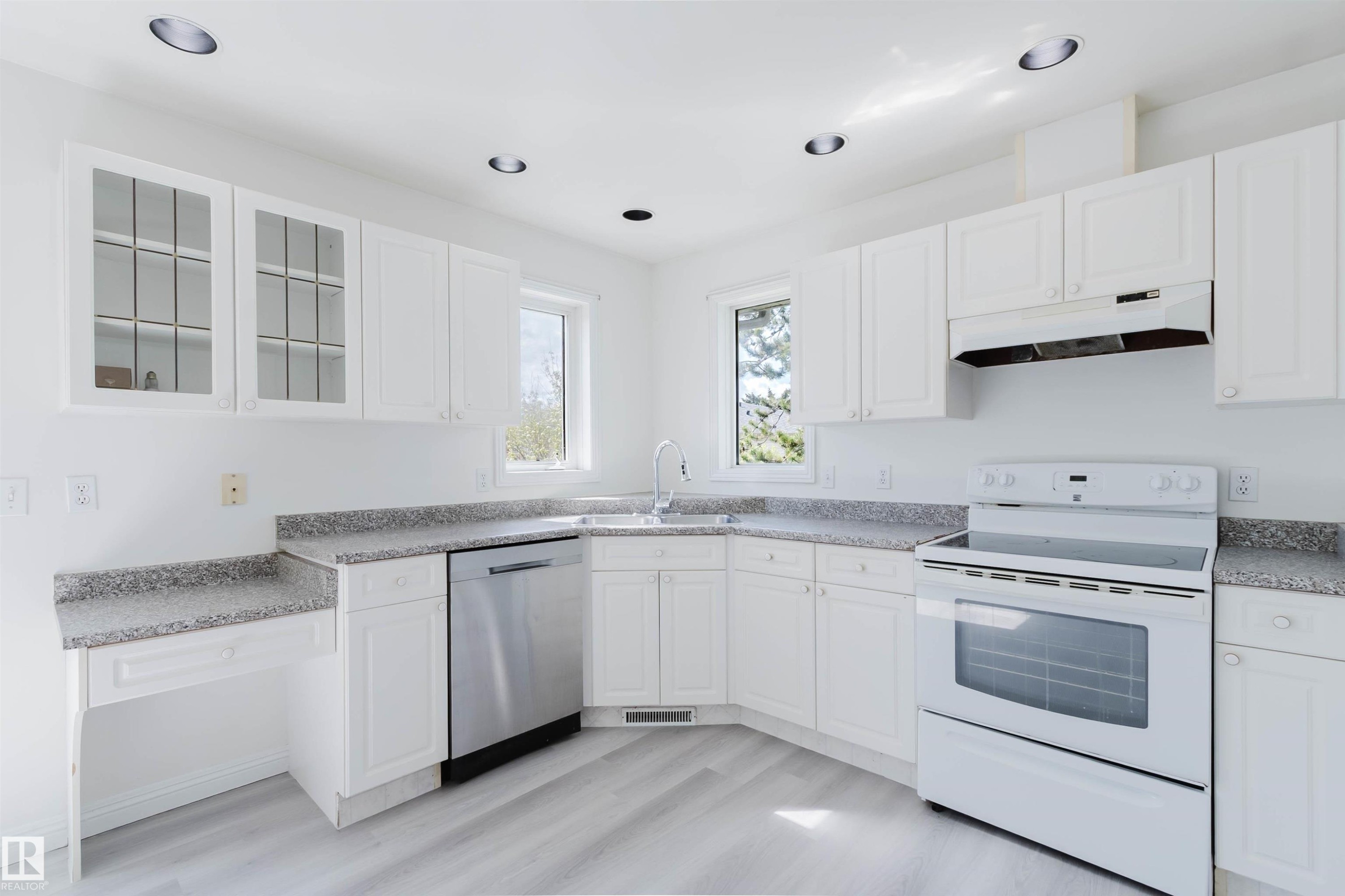 Kitchen featuring white cabinetry, light-toned countertops, stainless steel dishwasher, white electric range, and wood-finish flooring - 13755 131B Avenue, Edmonton, AB - Indoor Photo Showing Kitchen