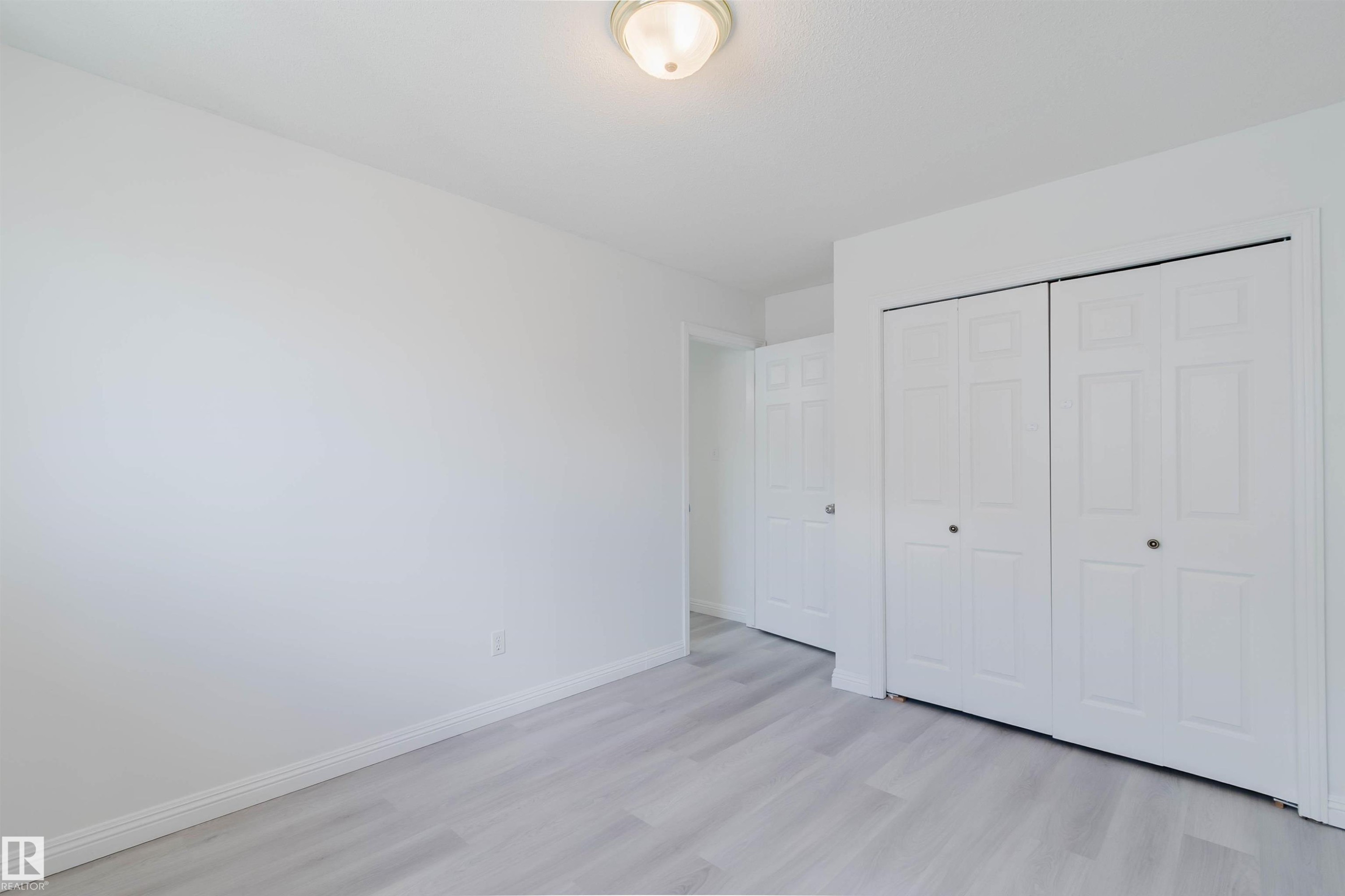 Room featuring light wood-finish flooring, white walls, and a ceiling-mounted light fixture - 13755 131B Avenue, Edmonton, AB - Indoor