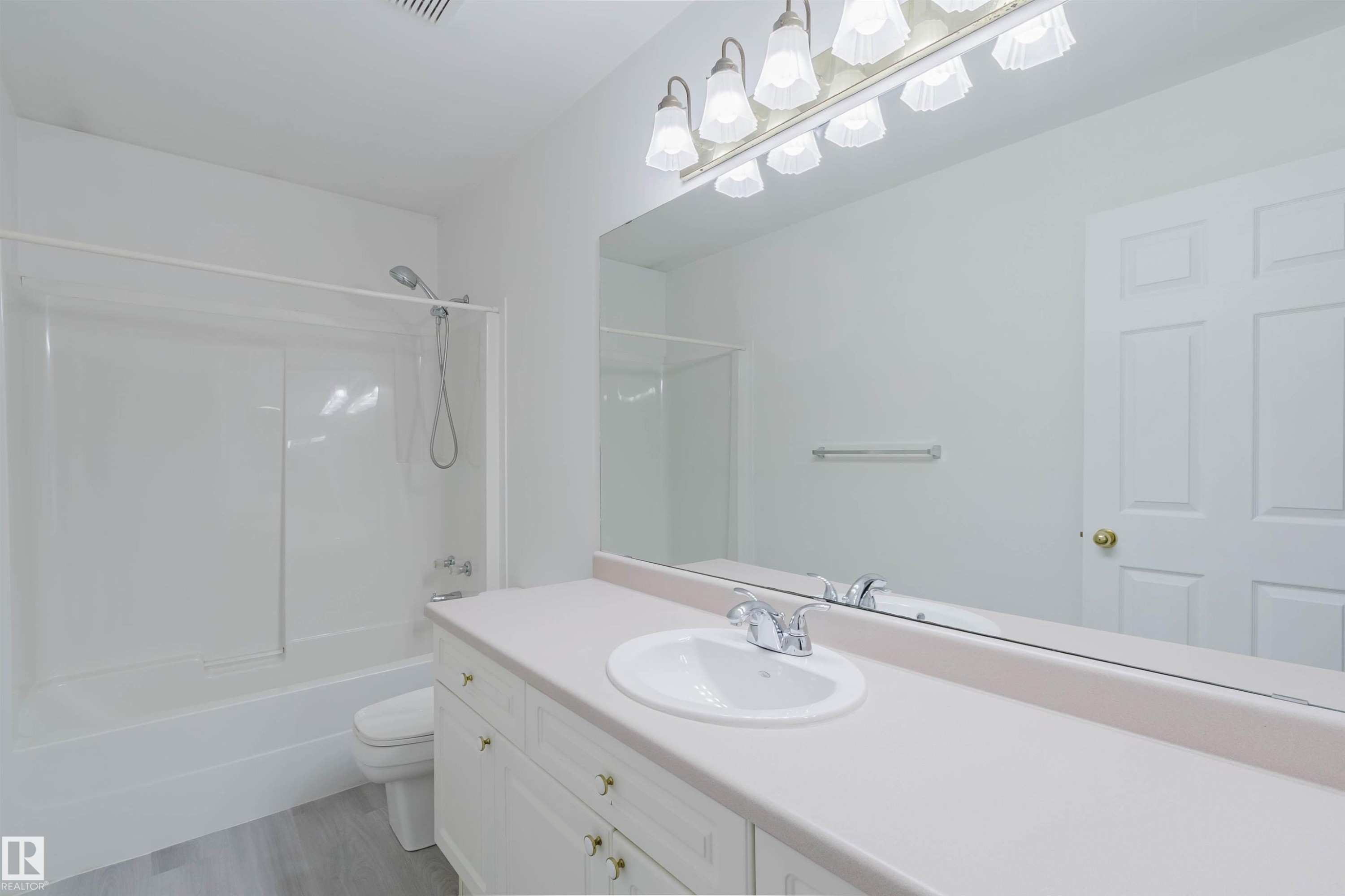 Bathroom vanity featuring a single basin sink, chrome faucet, and a large wall-mounted mirror - 13755 131B Avenue, Edmonton, AB - Indoor Photo Showing Bathroom