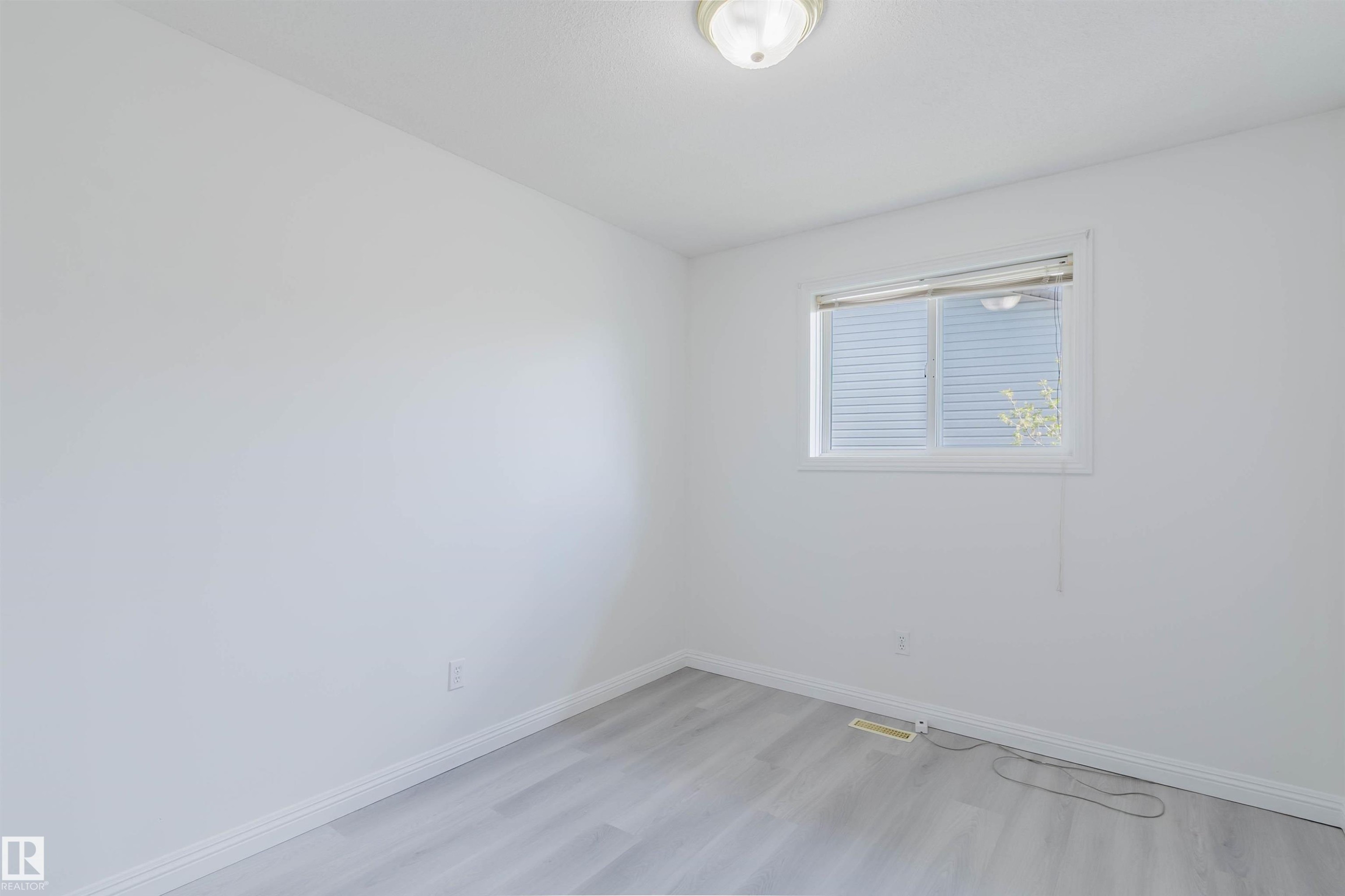 Bright interior space featuring light wood-finish flooring, white walls, and a window with blinds - 13755 131B Avenue, Edmonton, AB - Indoor Photo Showing Other Room