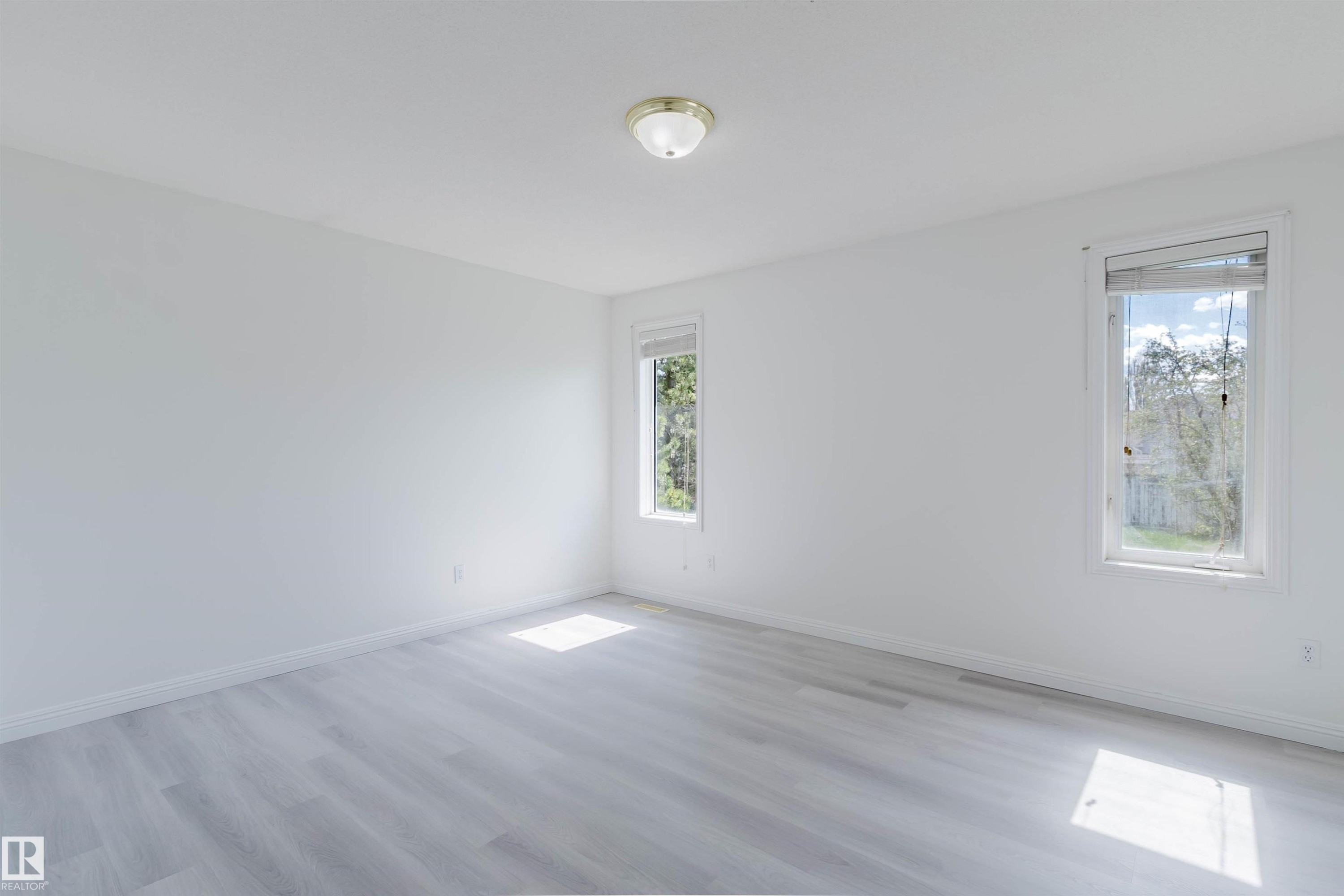 Spacious room featuring light wood-finish flooring, bright white walls, and two windows with white trim - 13755 131B Avenue, Edmonton, AB - Indoor Photo Showing Other Room