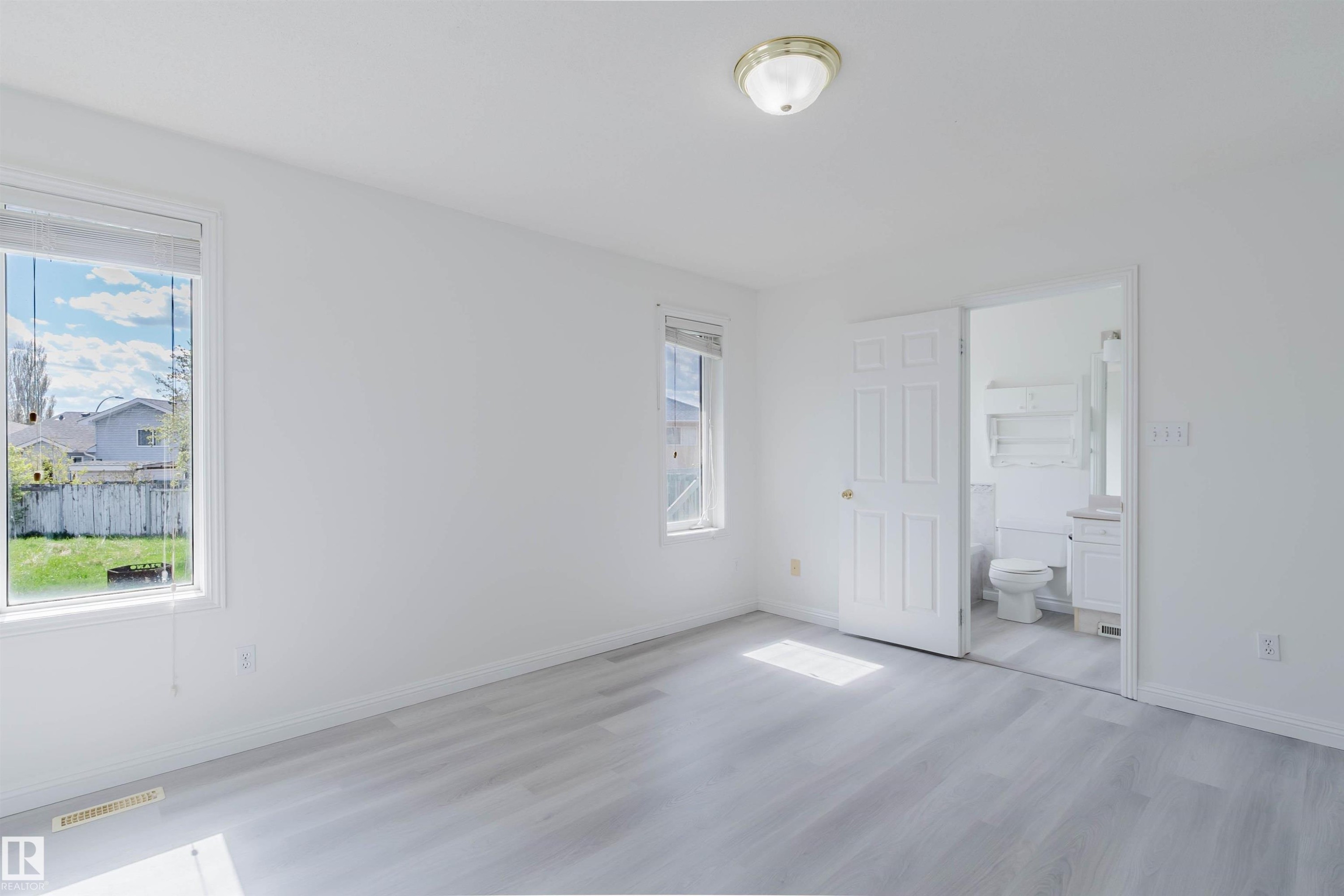 Bright interior space featuring light wood-finish flooring, white walls, and two windows - 13755 131B Avenue, Edmonton, AB - Indoor Photo Showing Other Room