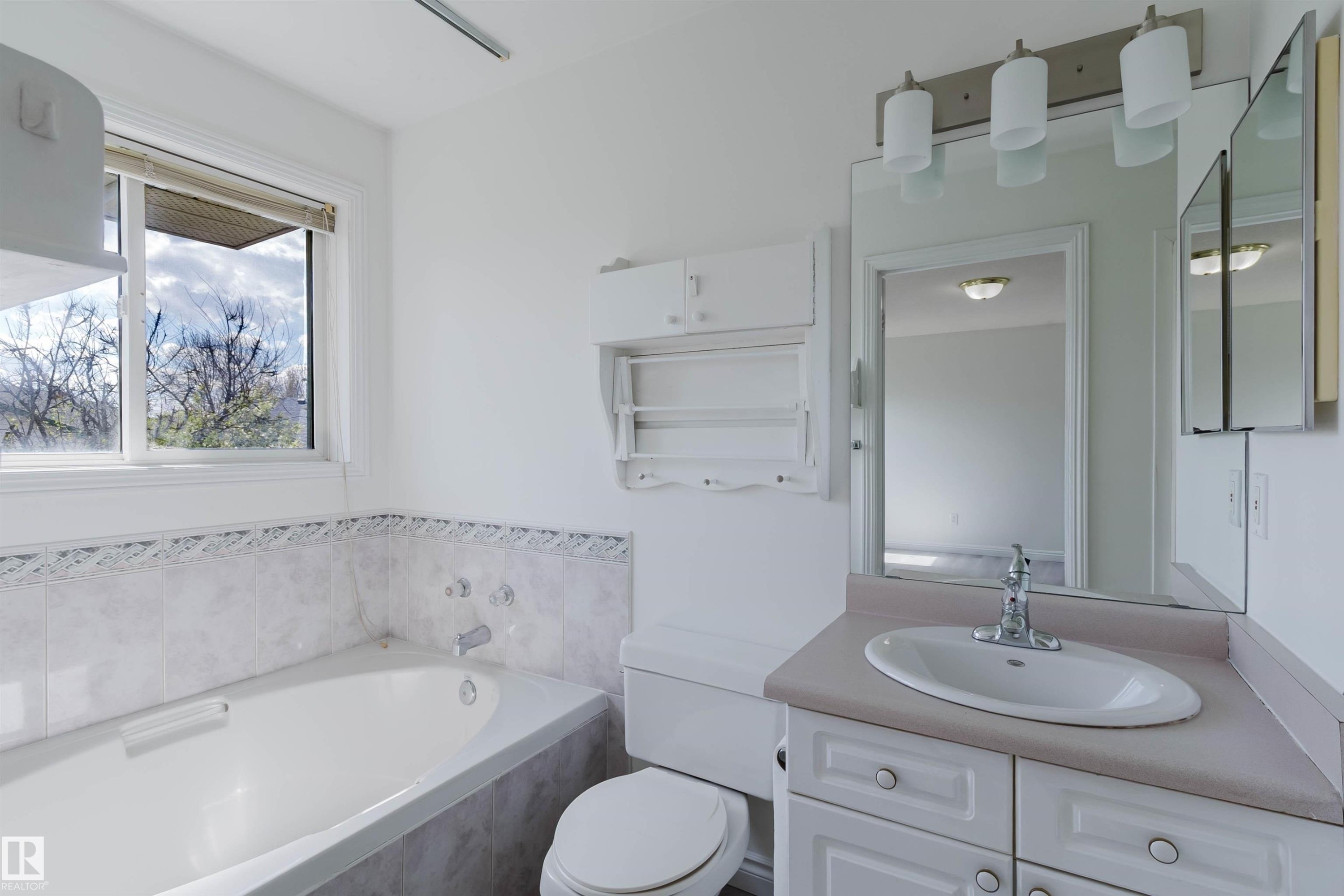 Bathroom featuring a built-in tub with tile surround, a single vanity with an integrated sink, and an overhead lighting fixture - 13755 131B Avenue, Edmonton, AB - Indoor Photo Showing Bathroom