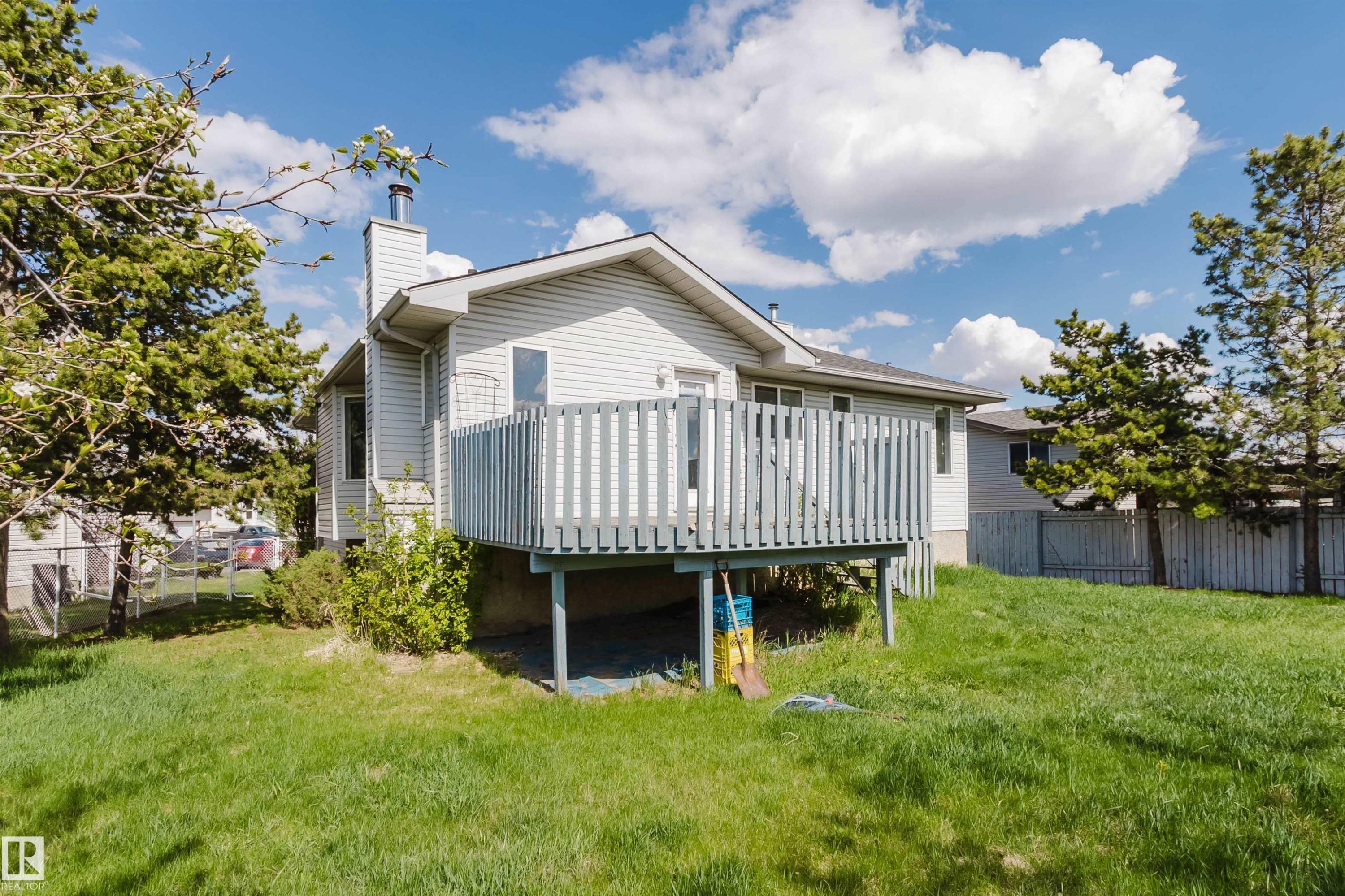 Expansive rear yard featuring a large elevated deck with wood railing, siding exterior, and mature trees - 13755 131B Avenue, Edmonton, AB - Outdoor With Deck Patio Veranda