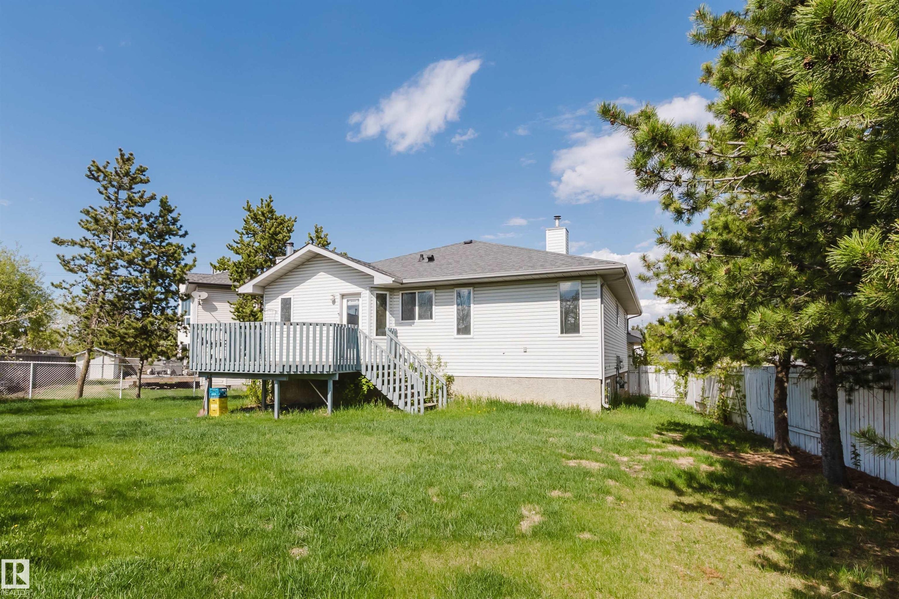 Rear exterior featuring white horizontal siding, a gray shingled roof, and a wooden deck with stairs - 13755 131B Avenue, Edmonton, AB - Outdoor