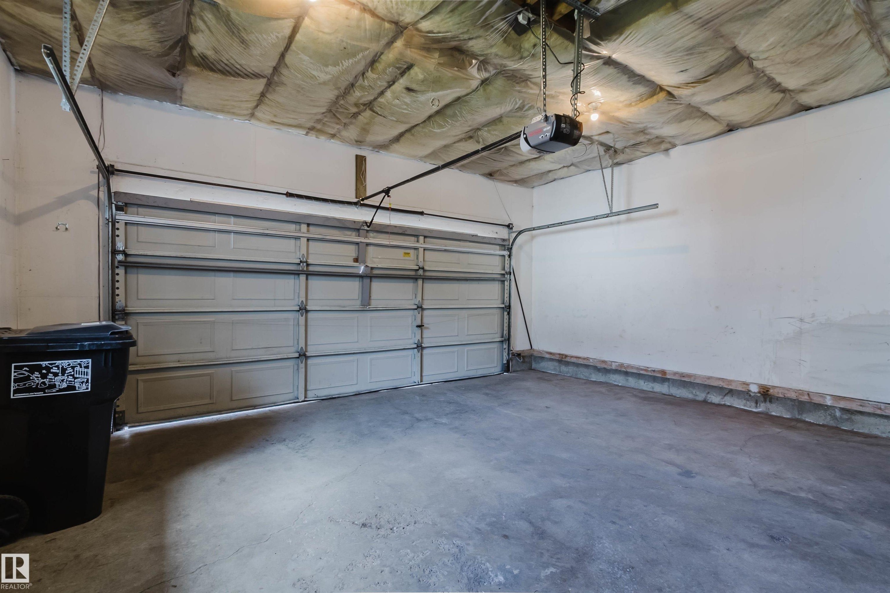 Garage interior featuring a concrete floor, white painted walls, and an automatic garage door opener - 13755 131B Avenue, Edmonton, AB - Indoor Photo Showing Garage