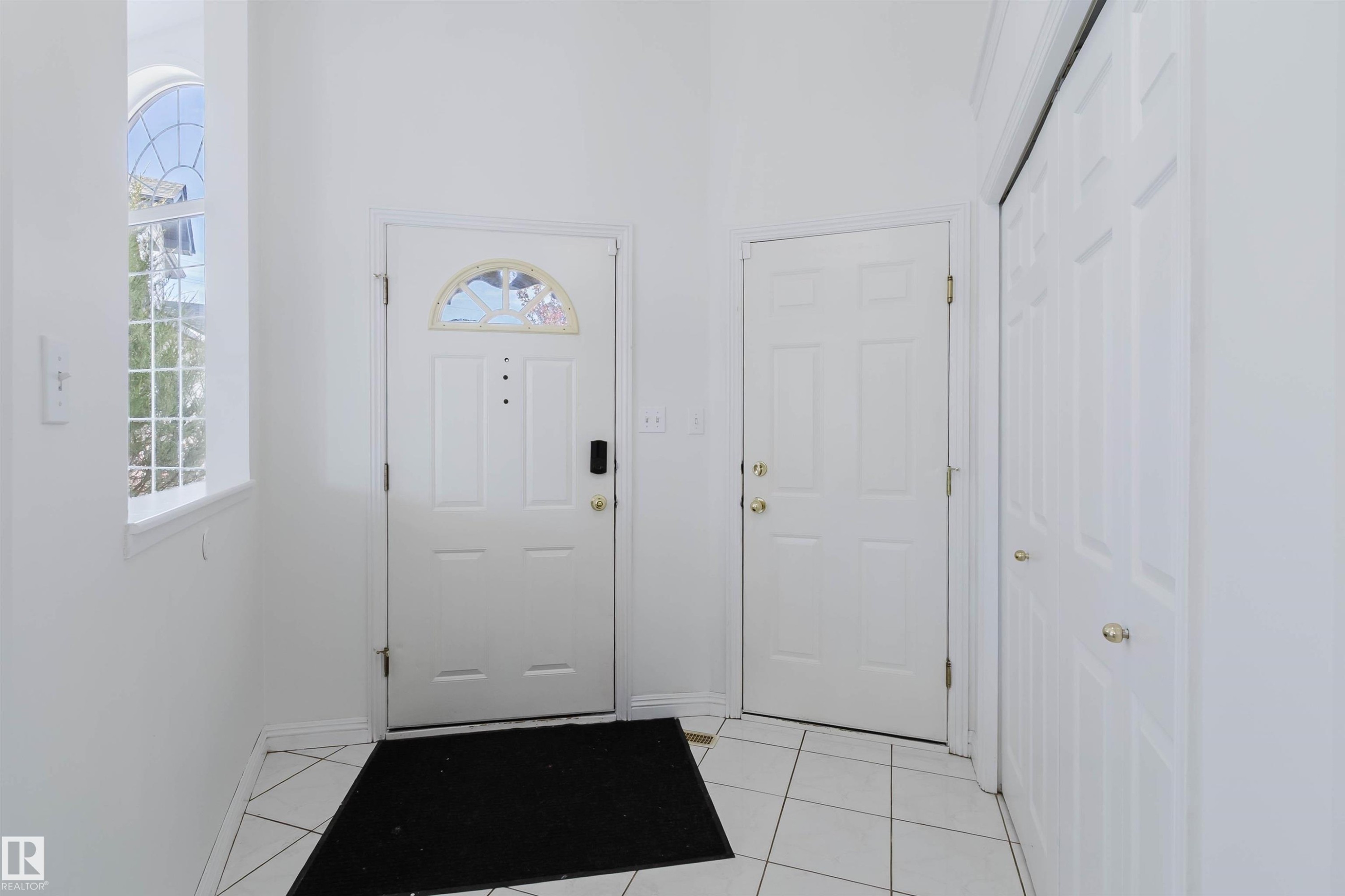 Entryway with white panel doors, arch-top window, and tiled flooring - 13755 131B Avenue, Edmonton, AB - Indoor Photo Showing Other Room