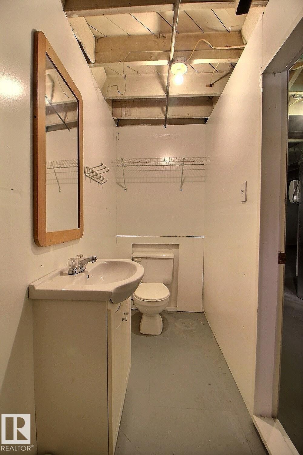 Compact bathroom featuring a pedestal sink with chrome faucet, toilet, and neutral tile flooring - 11626 87 Street Nw, Edmonton, AB - Indoor Photo Showing Bathroom