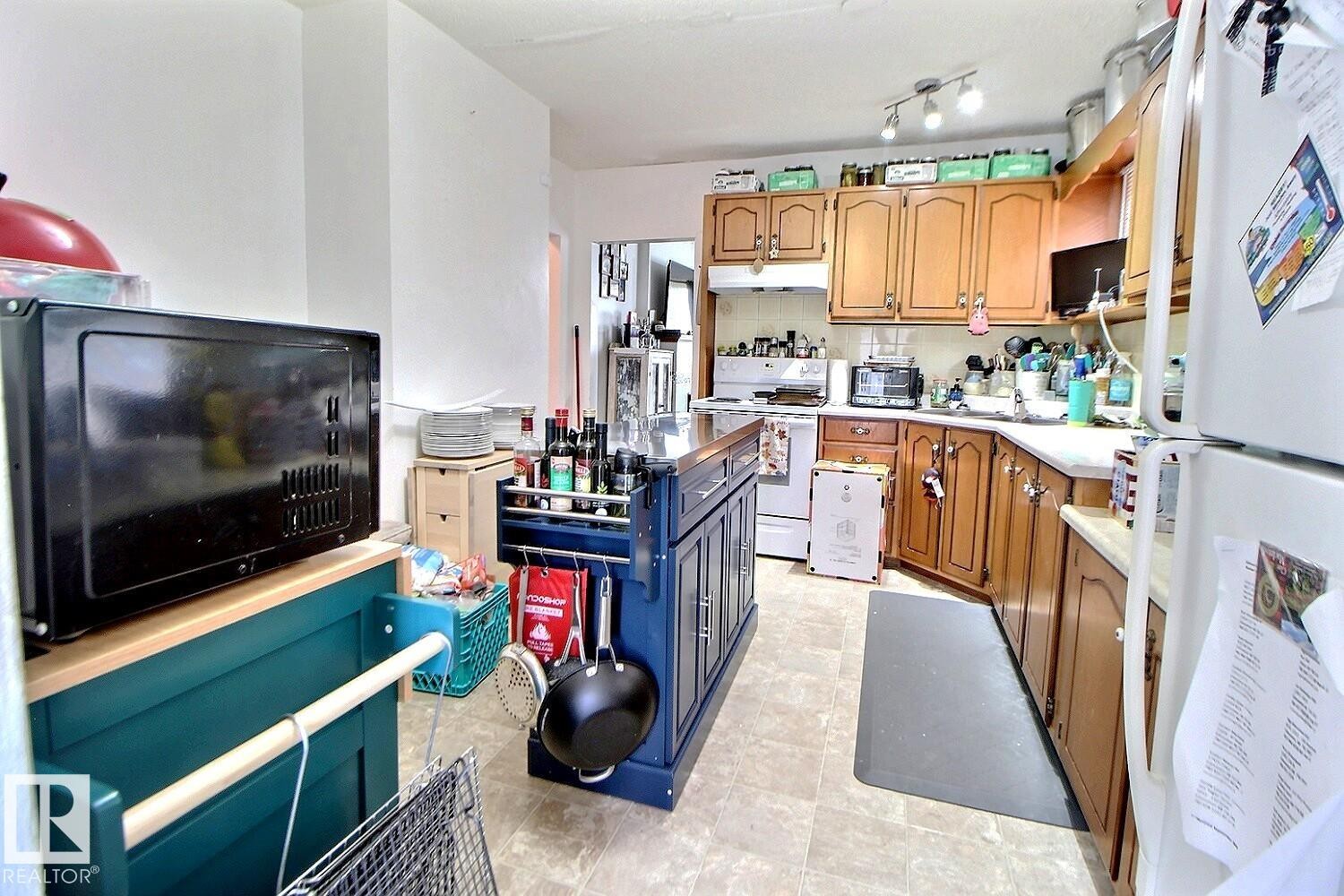 Kitchen featuring wood-finish cabinetry, a central island with storage, and integrated appliances - 11626 87 Street, Edmonton, AB - Indoor Photo Showing Kitchen