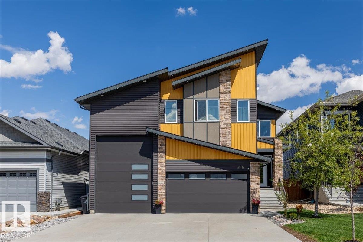 Contemporary two-story exterior featuring a dramatic angled roofline, contrasting yellow and dark grey siding, and stone accents - 219 Cranberry Bend, Fort Saskatchewan, AB - Outdoor