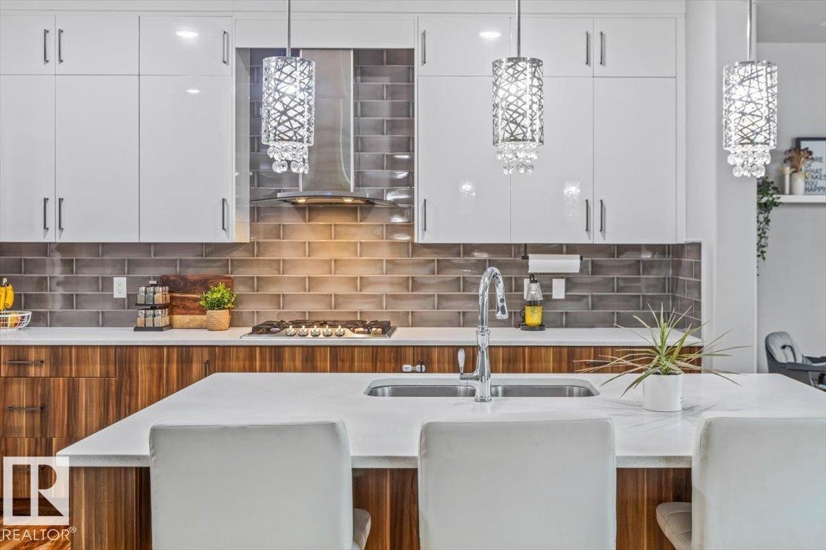 Modern kitchen featuring a large island with an undermount sink and chrome faucet - 219 Cranberry Bend, Fort Saskatchewan, AB - Indoor Photo Showing Kitchen With Double Sink With Upgraded Kitchen