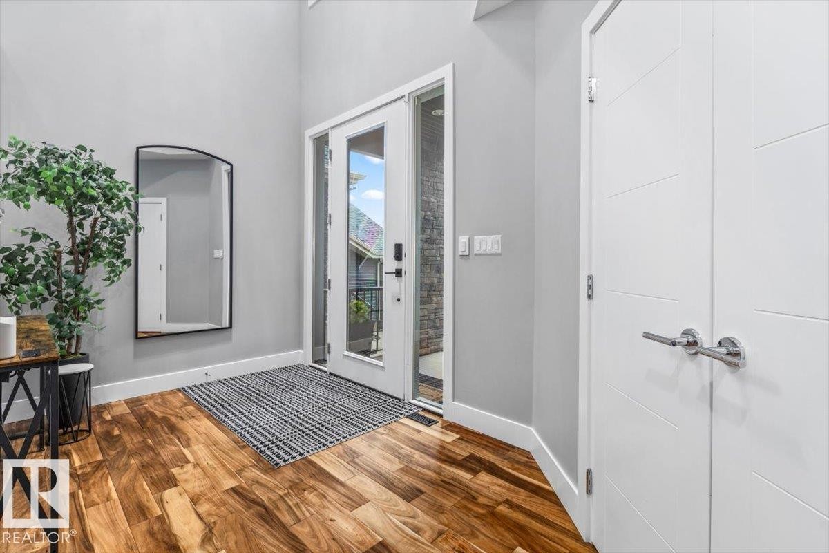Entryway featuring a front door with sidelights, wood-finish flooring, and high ceilings - 219 Cranberry Bend, Fort Saskatchewan, AB - Indoor Photo Showing Other Room