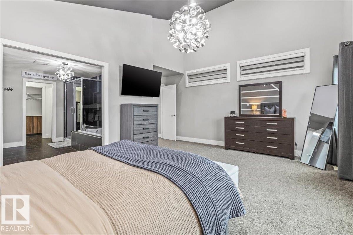 Spacious room featuring vaulted ceilings, a contemporary ceiling light fixture, two horizontal transom windows, and light gray wall paint - 219 Cranberry Bend, Fort Saskatchewan, AB - Indoor Photo Showing Bedroom