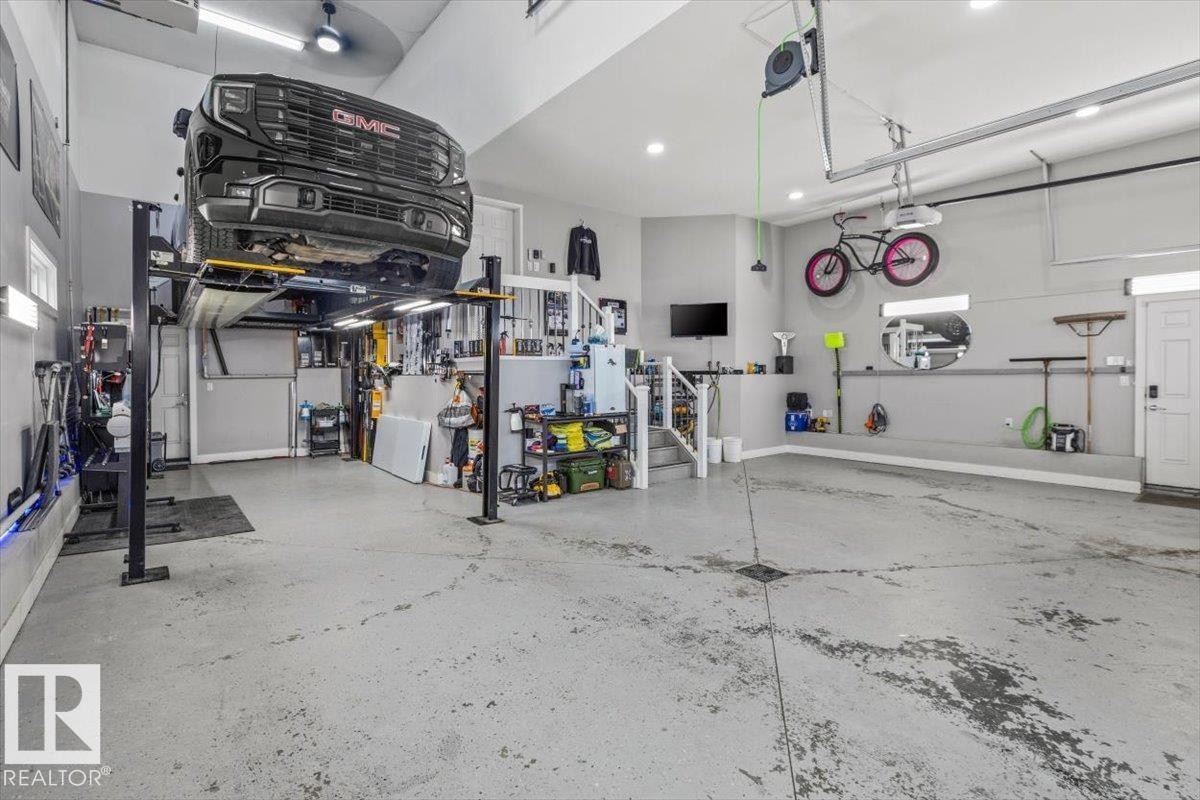 Spacious garage featuring a vehicle lift, concrete flooring, overhead lighting, and ample storage solutions - 219 Cranberry Bend, Fort Saskatchewan, AB - Indoor Photo Showing Garage