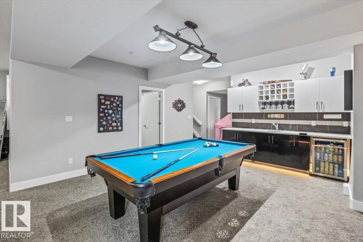 Recreation room featuring a pool table with overhead lighting, built-in cabinetry, an integrated wet bar, and a beverage cooler - 219 Cranberry Bend, Fort Saskatchewan, AB - Indoor Photo Showing Other Room