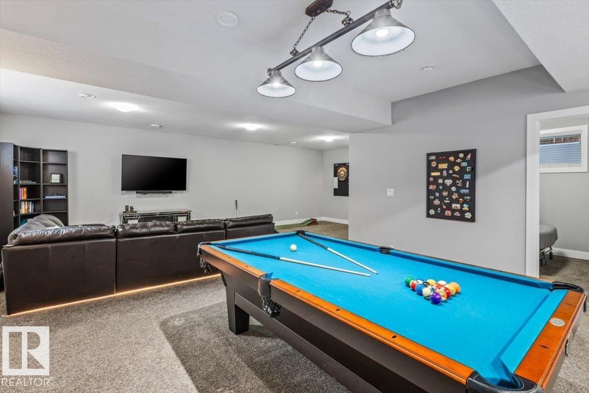 Spacious recreation room featuring a pool table with a dedicated overhead light fixture, recessed ceiling lighting, and soft carpet flooring - 219 Cranberry Bend, Fort Saskatchewan, AB - Indoor Photo Showing Other Room