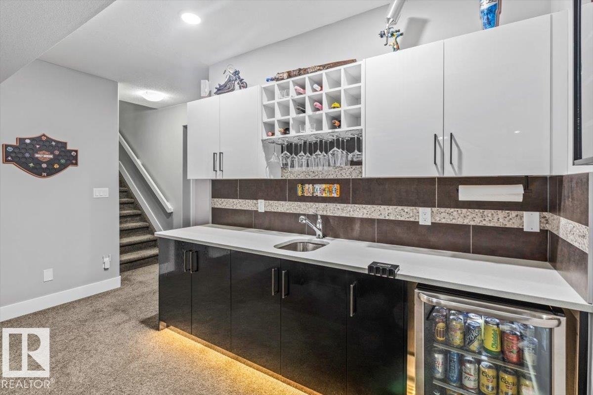 Built-in wet bar featuring a beverage refrigerator, sink, and under-cabinet lighting - 219 Cranberry Bend, Fort Saskatchewan, AB - Indoor Photo Showing Kitchen