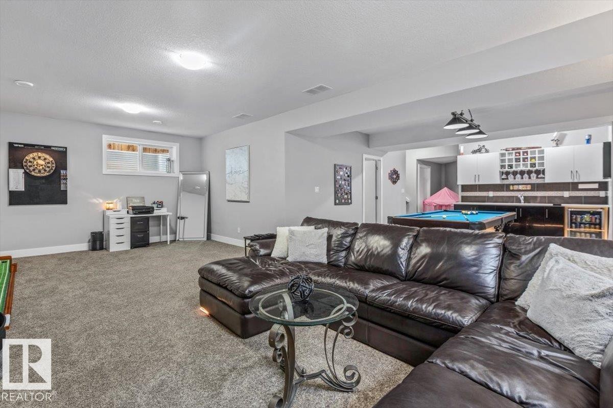 Spacious lower-level entertainment area featuring recessed lighting, a built-in wet bar with upper and lower cabinetry, a beverage refrigerator, and a pool table - 219 Cranberry Bend, Fort Saskatchewan, AB - Indoor Photo Showing Living Room