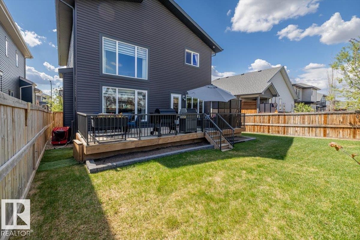 Rear exterior featuring dark horizontal siding and multiple windows - 219 Cranberry Bend, Fort Saskatchewan, AB - Outdoor With Deck Patio Veranda