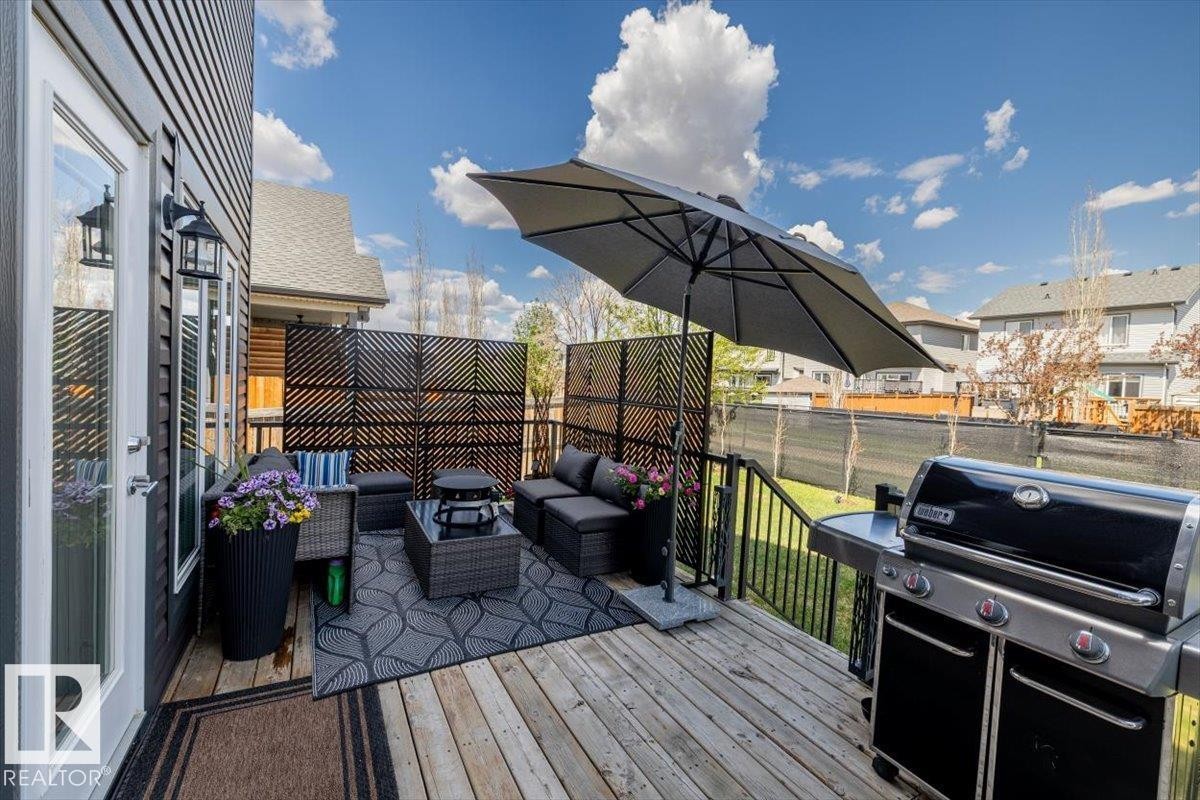 Expansive outdoor deck featuring wood flooring, black metal railings, and decorative privacy screens - 219 Cranberry Bend, Fort Saskatchewan, AB - Outdoor With Exterior