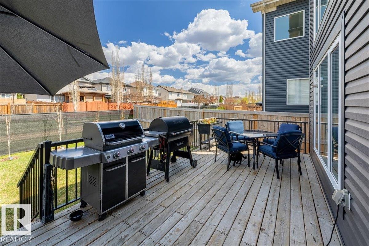 Spacious outdoor deck featuring natural wood-finish planks, dark metal railings, and direct access to a grassy yard - 219 Cranberry Bend, Fort Saskatchewan, AB - Outdoor With Deck Patio Veranda With Exterior
