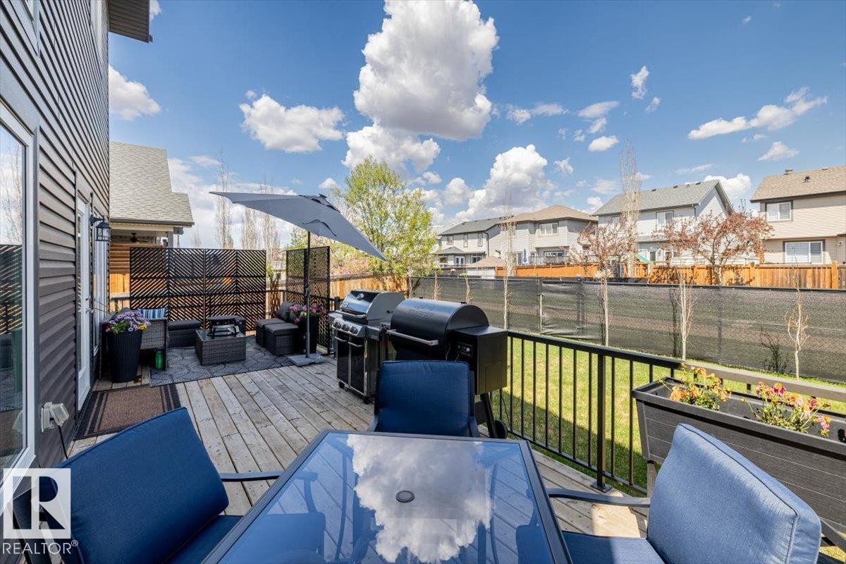 Expansive wooden deck featuring black metal railings and a dedicated patio area - 219 Cranberry Bend, Fort Saskatchewan, AB - Outdoor With Exterior
