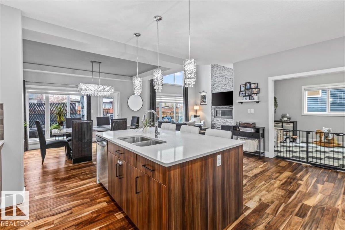 Kitchen island featuring a double-basin sink, stainless steel faucet, and white countertop - 219 Cranberry Bend, Fort Saskatchewan, AB - Indoor Photo Showing Kitchen With Double Sink
