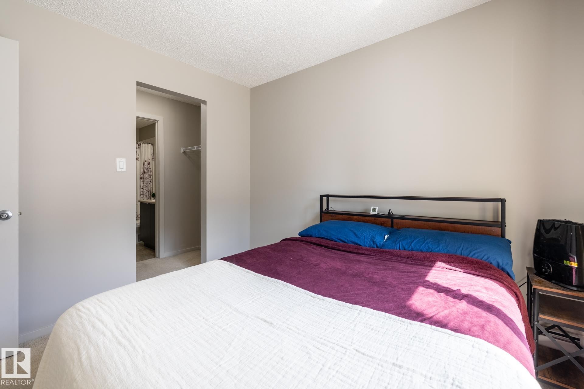 Carpeted bedroom with neutral wall tones and a textured ceiling finish - 131 344 Windermere Road, Edmonton, AB - Indoor Photo Showing Bedroom