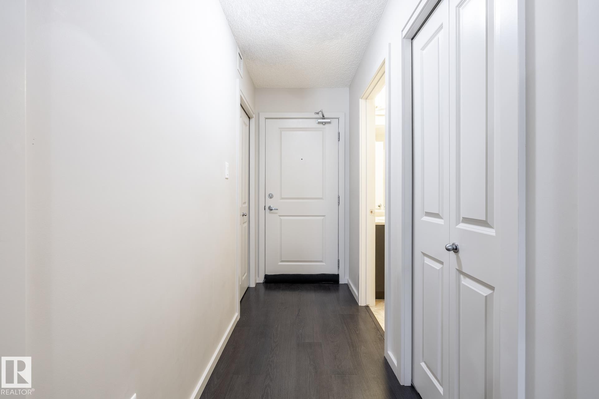 Entryway featuring dark wood-finish flooring, white walls, and a paneled front door - 131 344 Windermere Road, Edmonton, AB - Indoor Photo Showing Other Room