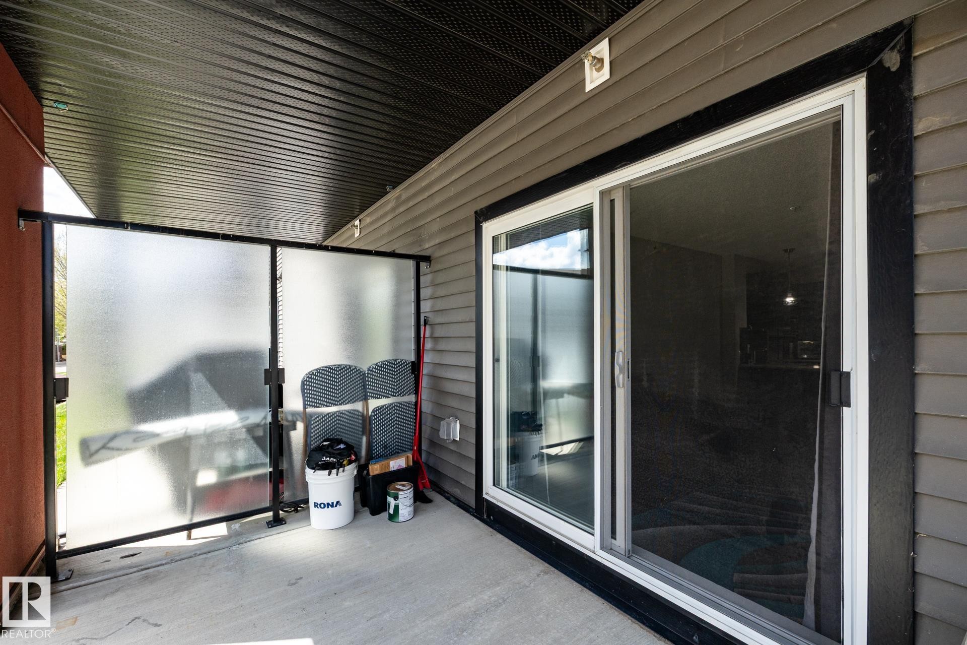 Covered concrete patio featuring a sliding glass door with screen, horizontal siding, and a translucent privacy screen - 131 344 Windermere Road, Edmonton, AB - Outdoor With Deck Patio Veranda With Exterior