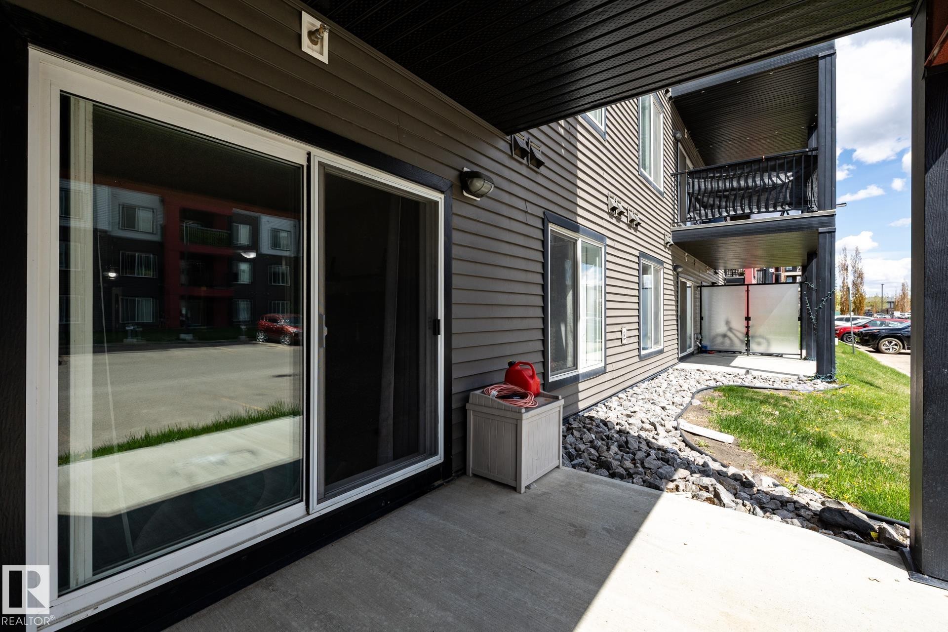Ground-level patio with a concrete surface and dark siding exterior - 131 344 Windermere Road, Edmonton, AB - Outdoor With Exterior