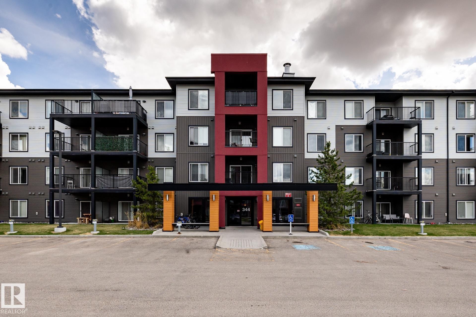 Modern multi-story building featuring a prominent central entrance with a red accent facade - 131 344 Windermere Road, Edmonton, AB - Outdoor With Facade