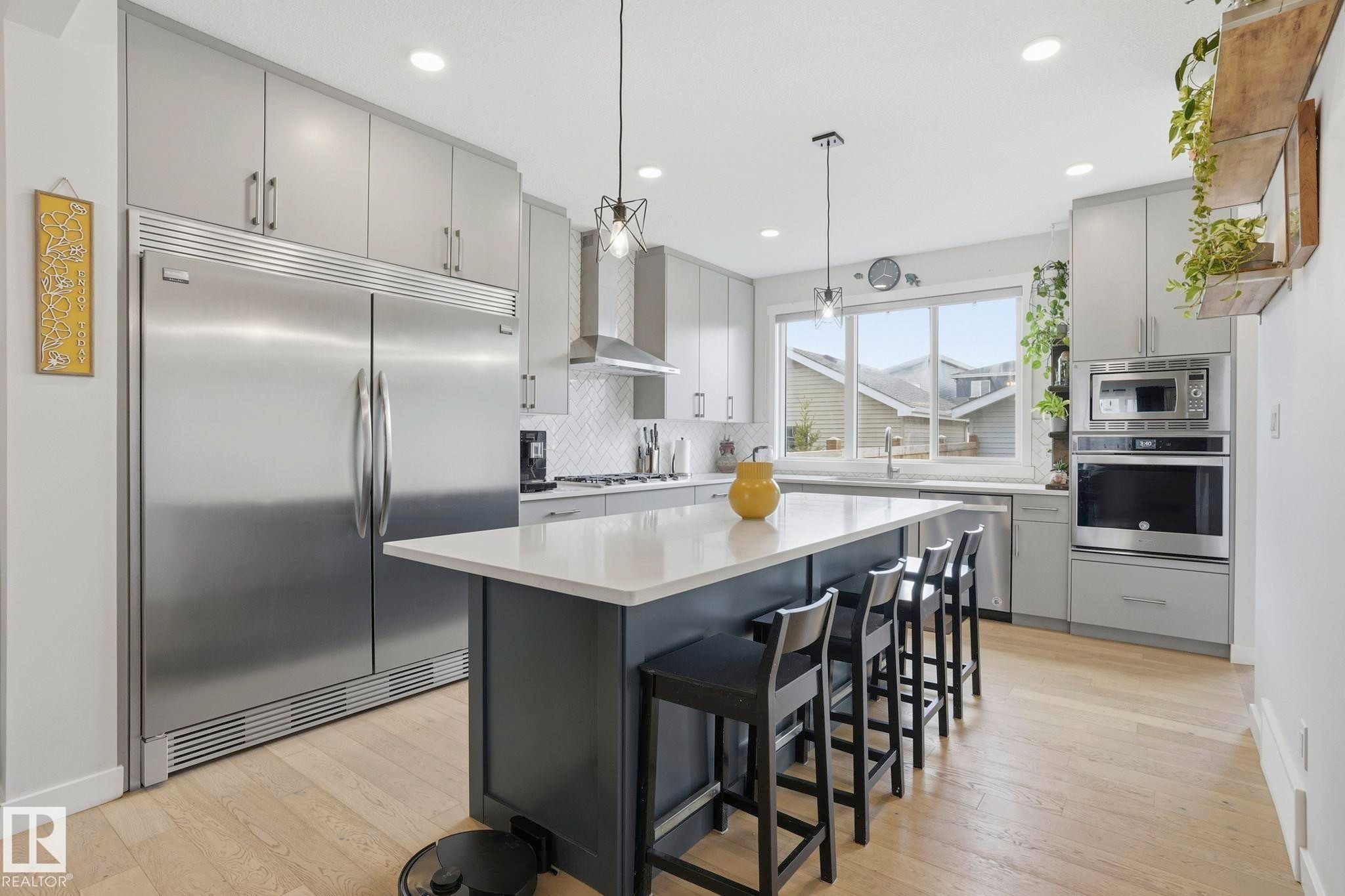 Modern kitchen featuring light wood-finish flooring, custom gray cabinetry, and a large central island with seating - 2116 159 Street, Edmonton, AB - Indoor Photo Showing Kitchen With Upgraded Kitchen