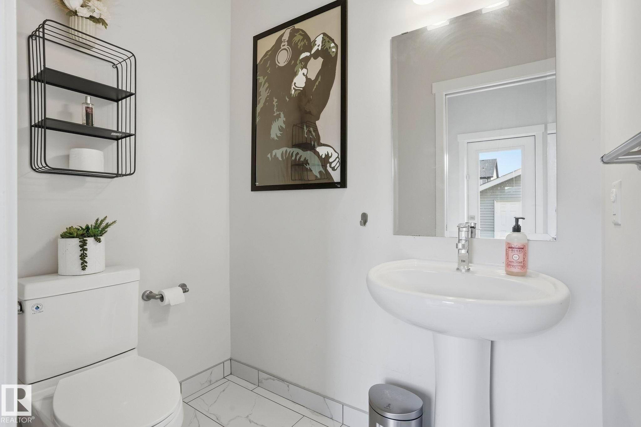 Pedestal sink with chrome faucet, complemented by a rectangular frameless mirror and an overhead light fixture - 2116 159 Street, Edmonton, AB - Indoor Photo Showing Bathroom