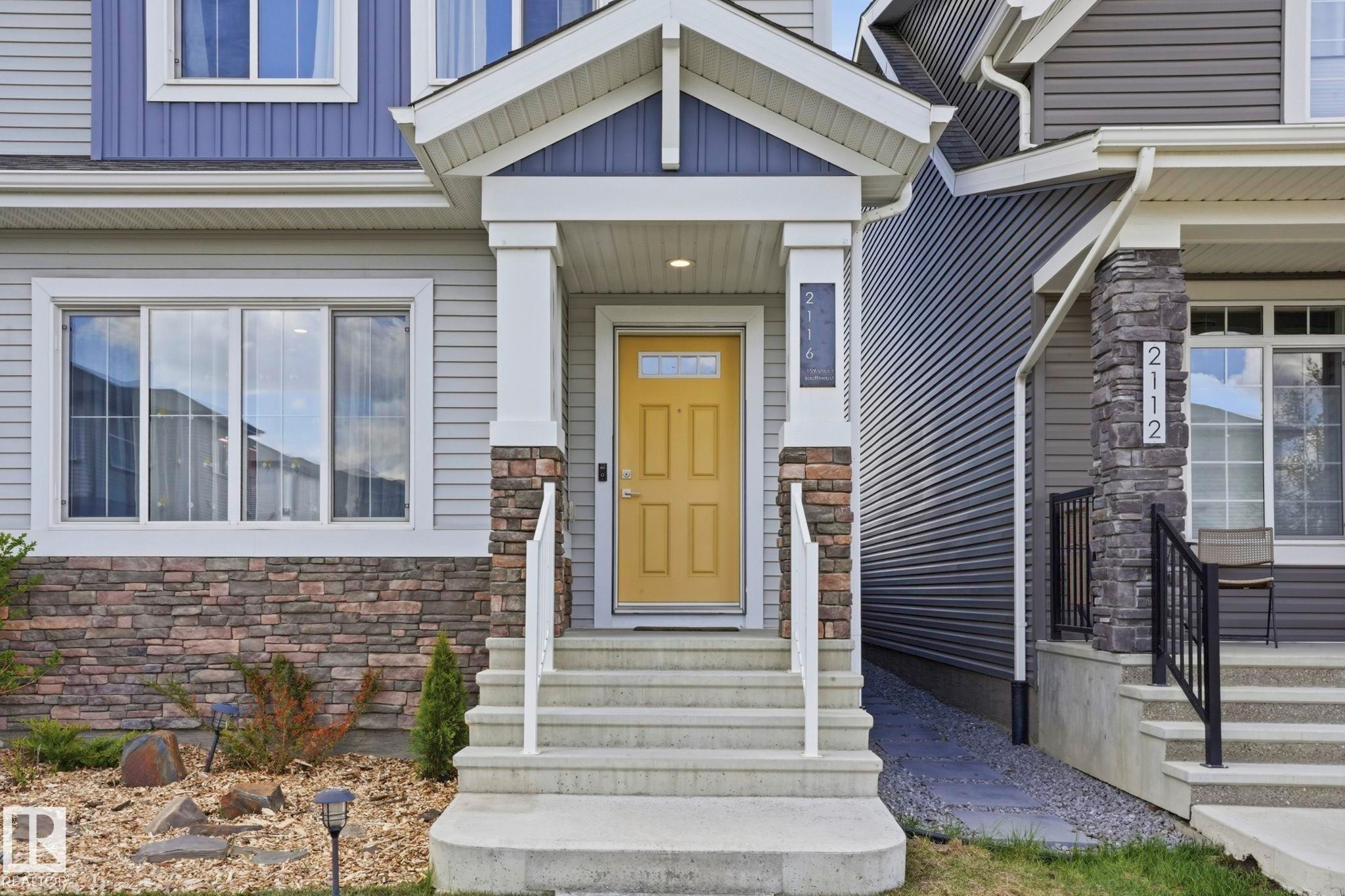 Exterior featuring a covered porch, stone veneer accents, and a bright yellow entry door - 2116 159 Street, Edmonton, AB - Outdoor With Facade