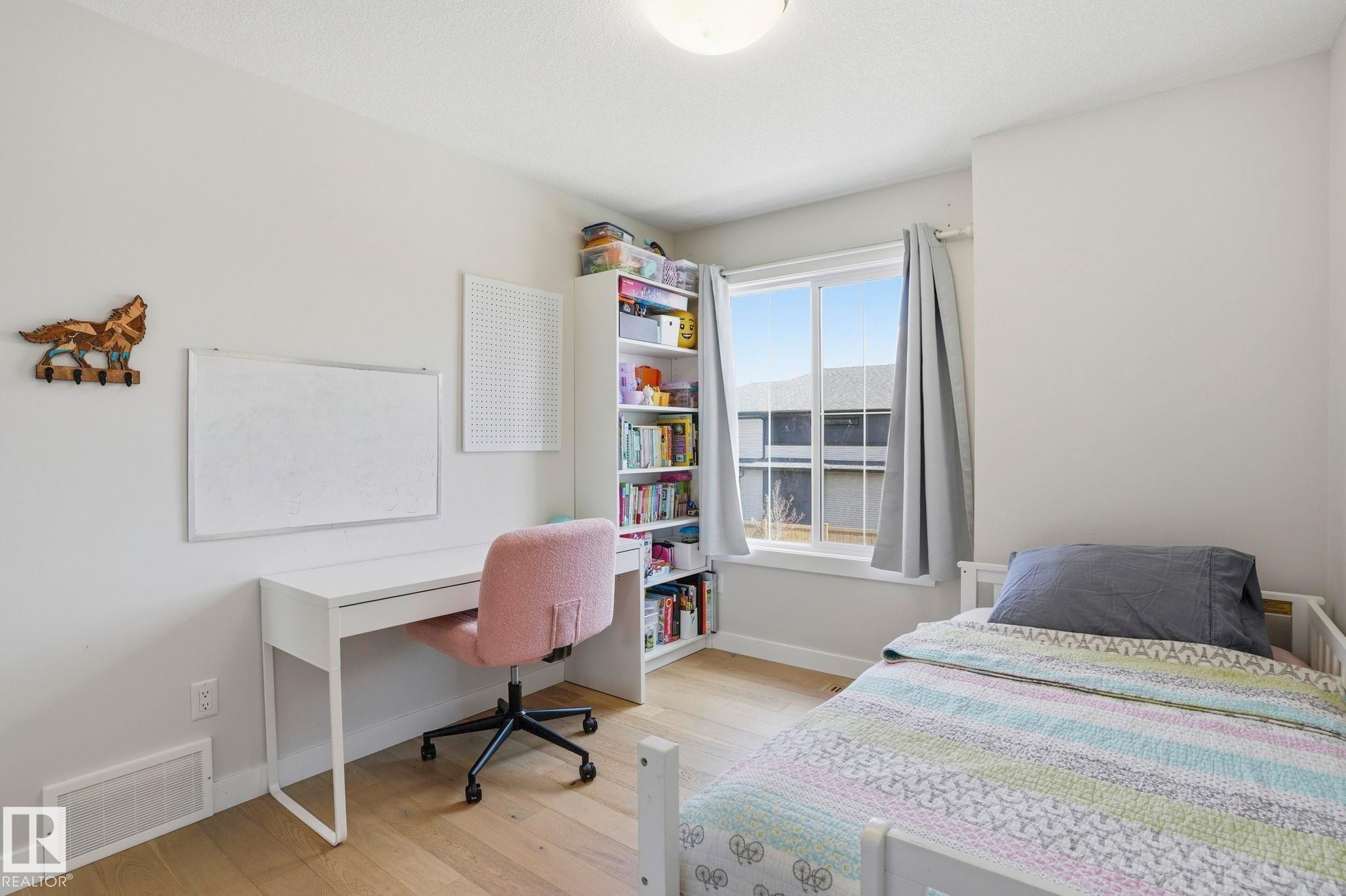 Bright room featuring a window with natural light, wood-finish flooring, and a ceiling-mounted light fixture - 2116 159 Street, Edmonton, AB - Indoor Photo Showing Bedroom