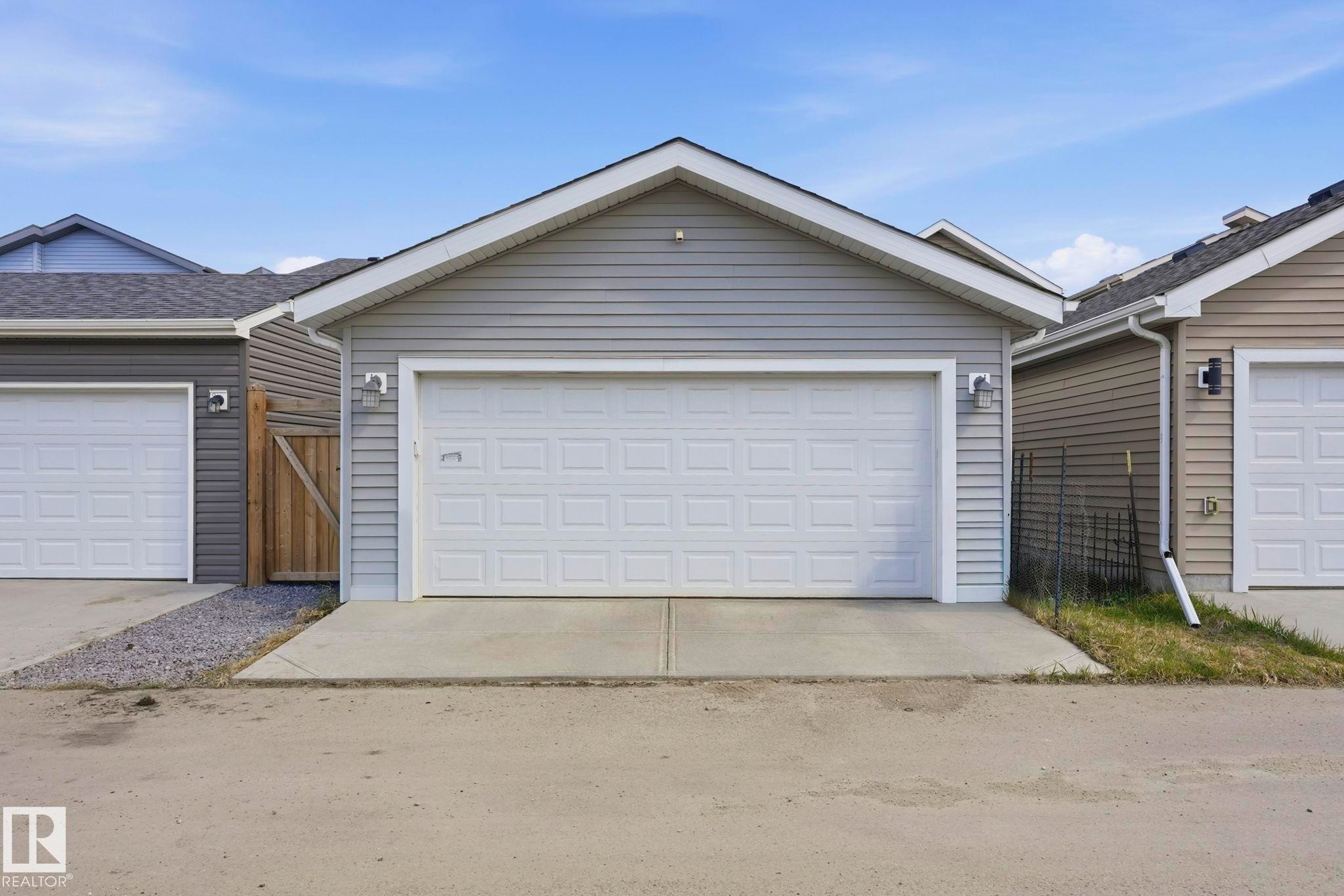 Detached garage featuring panel garage door, light grey siding, and concrete driveway - 2116 159 Street, Edmonton, AB - Outdoor