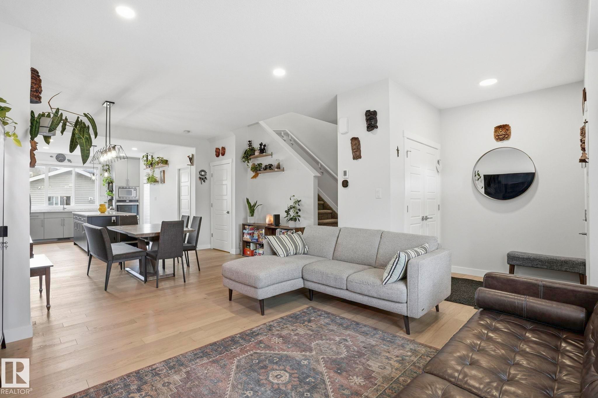 Open-concept living space featuring light wood-finish flooring, recessed lighting, and a contemporary pendant light fixture over the dining area - 2116 159 Street, Edmonton, AB - Indoor Photo Showing Living Room