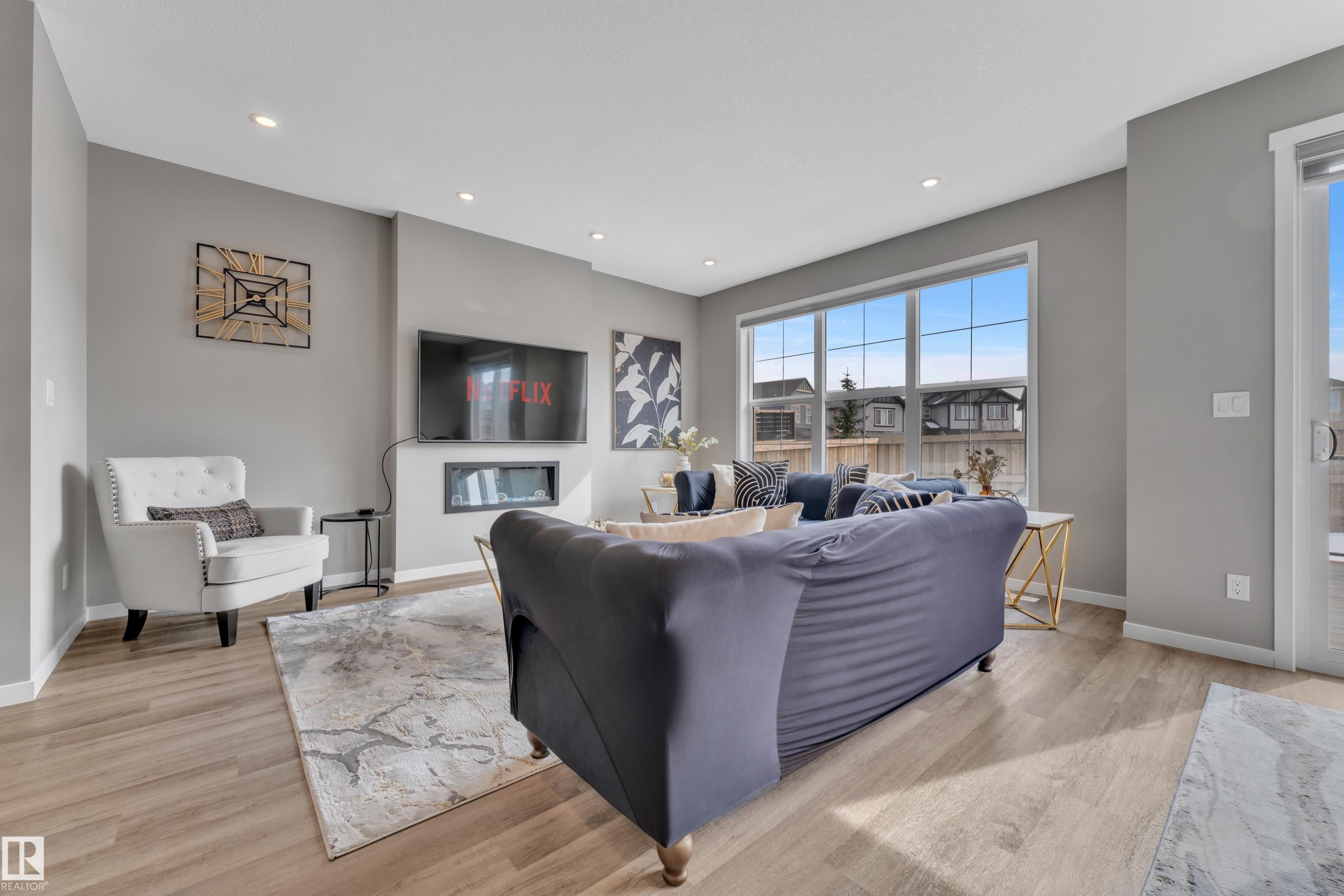 This inviting living area features light-toned flooring, recessed lighting, and a modern fireplace integrated into the wall - 21853 98A Avenue, Edmonton, AB - Indoor Photo Showing Living Room