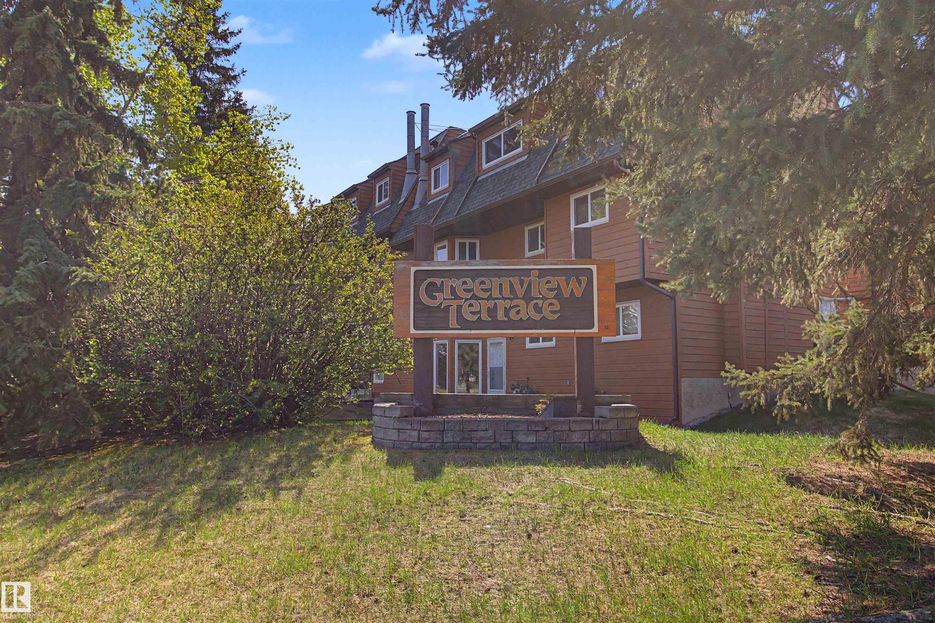 Greenview Terrace building exterior featuring brown siding, white-framed windows, and a multi-level roofline - 5953 40 Avenue, Edmonton, AB
