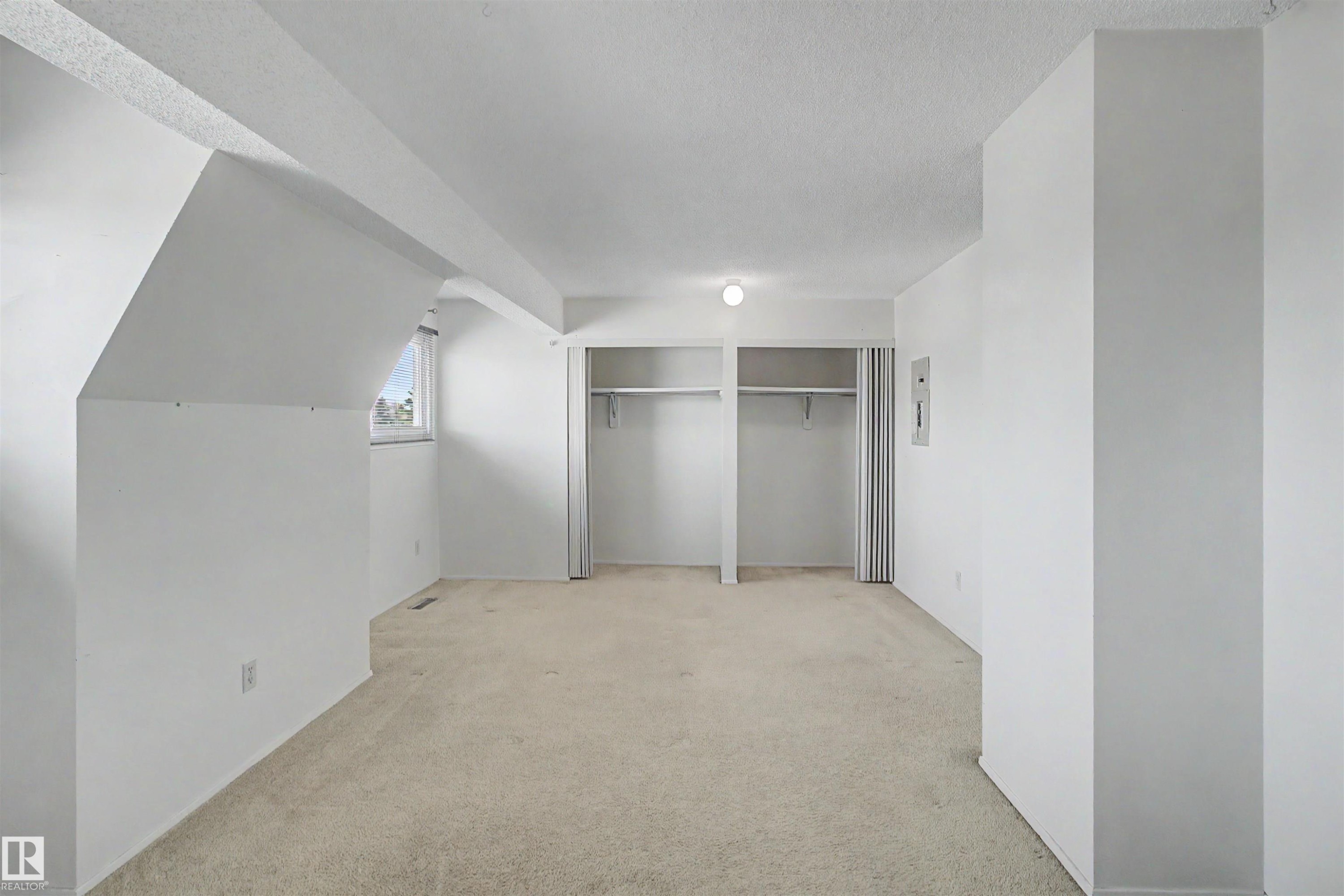 Carpeted room featuring white walls, a single window, and two integrated closet spaces with bi-fold doors - 5953 40 Avenue, Edmonton, AB
