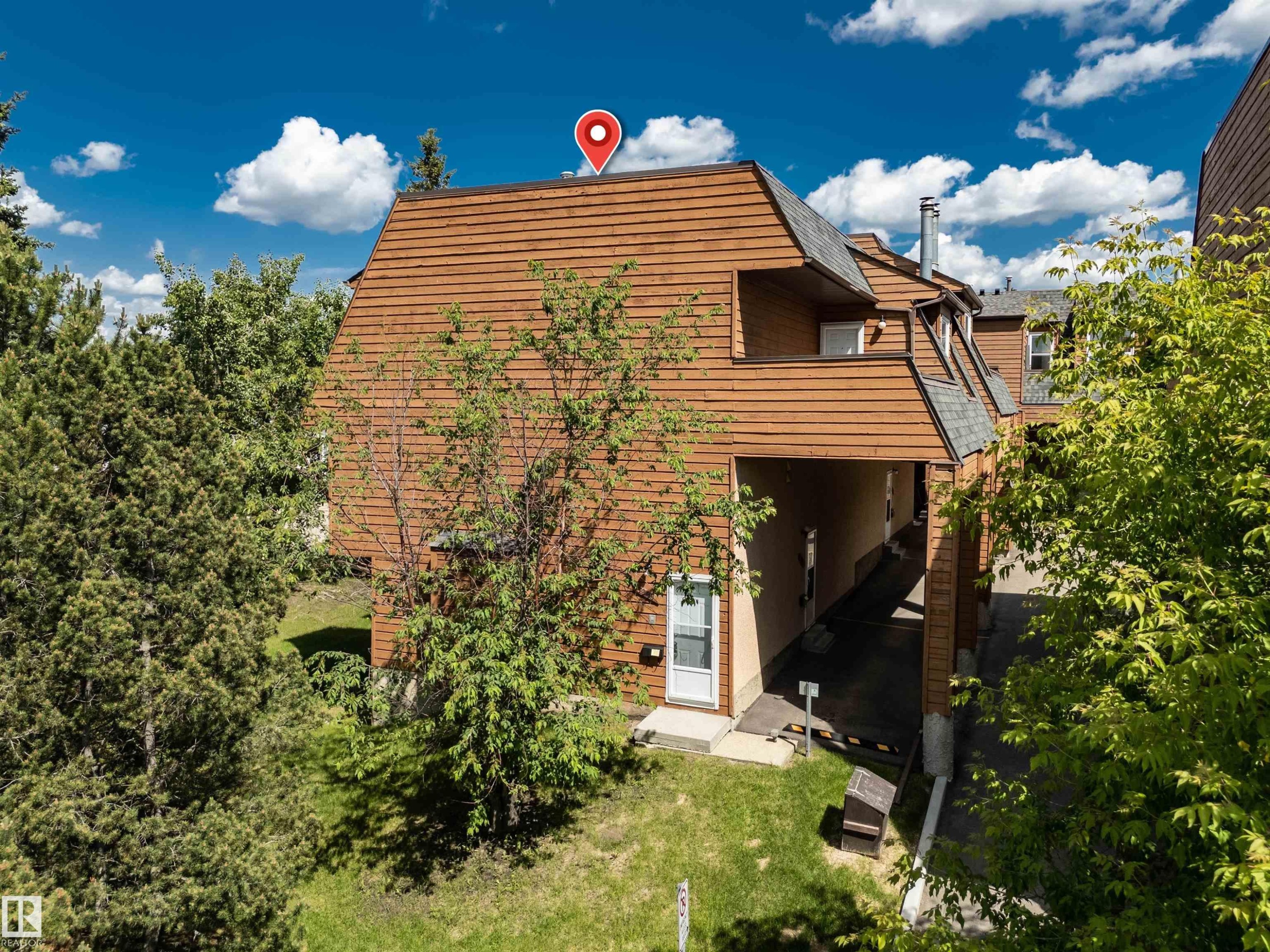 Multi-level exterior featuring a wood-shingle roof, wood-plank siding, and mature greenery - 5953 40 Avenue, Edmonton, AB